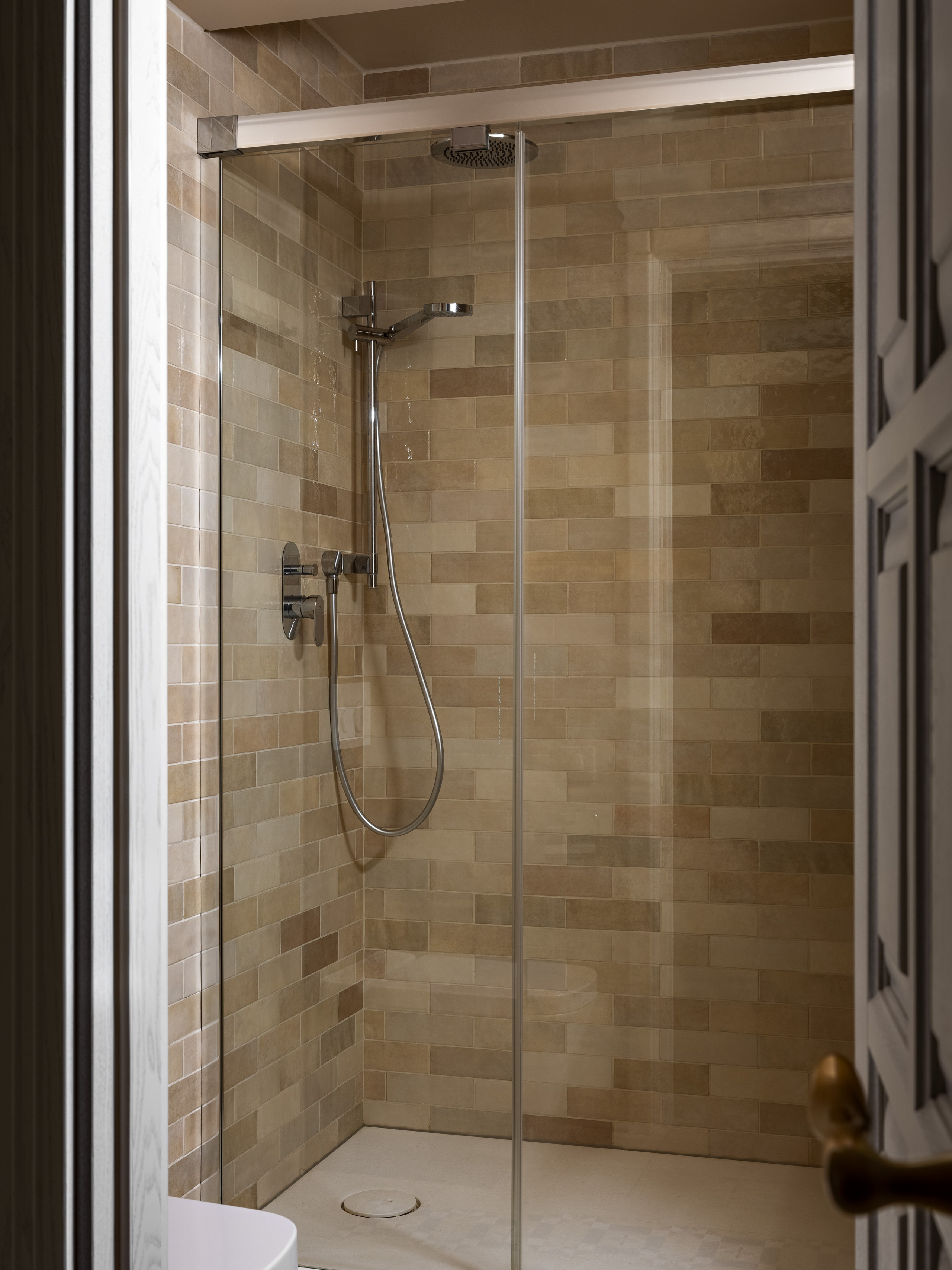 Современный санузел с душевой кабиной, отделанной бежевой плиткой под кирпич, стеклянной перегородкой и металлическим смесителем; проект дизайнеров Юлии Капункиной и Альбины Терещенко, стилист Алина Нелень, фото Сергея Денисенко.