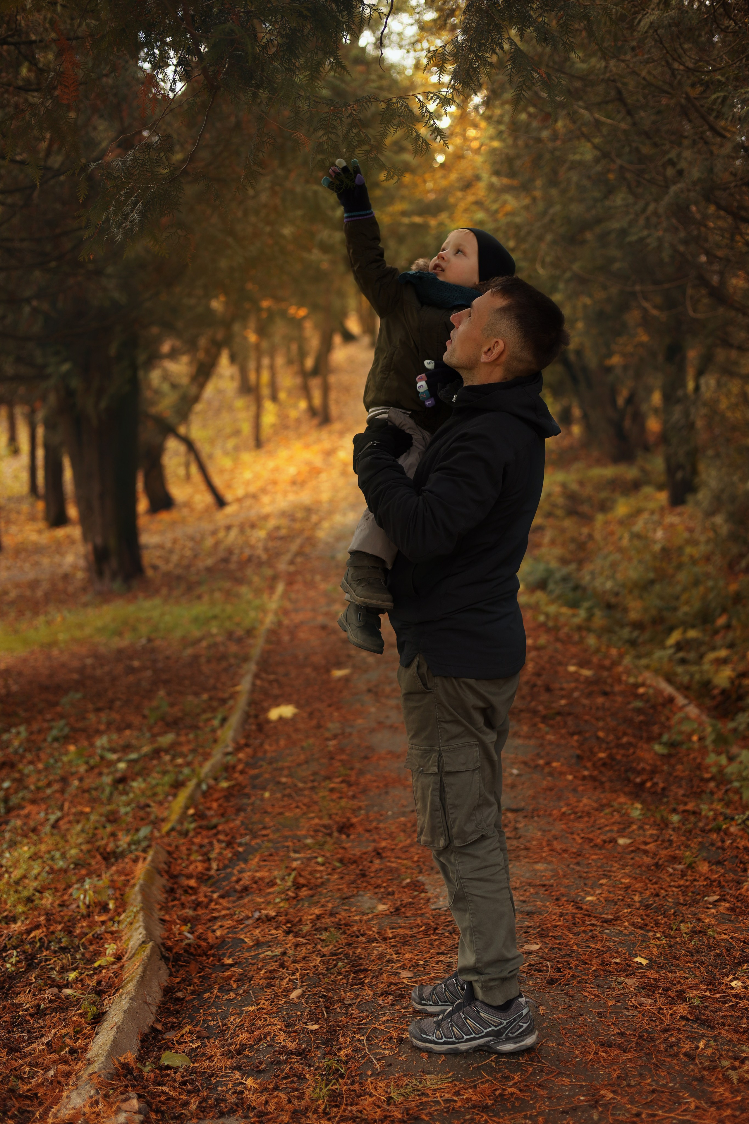 фотосессия с ребенком папа держит сына на руках а он тянется к веткам