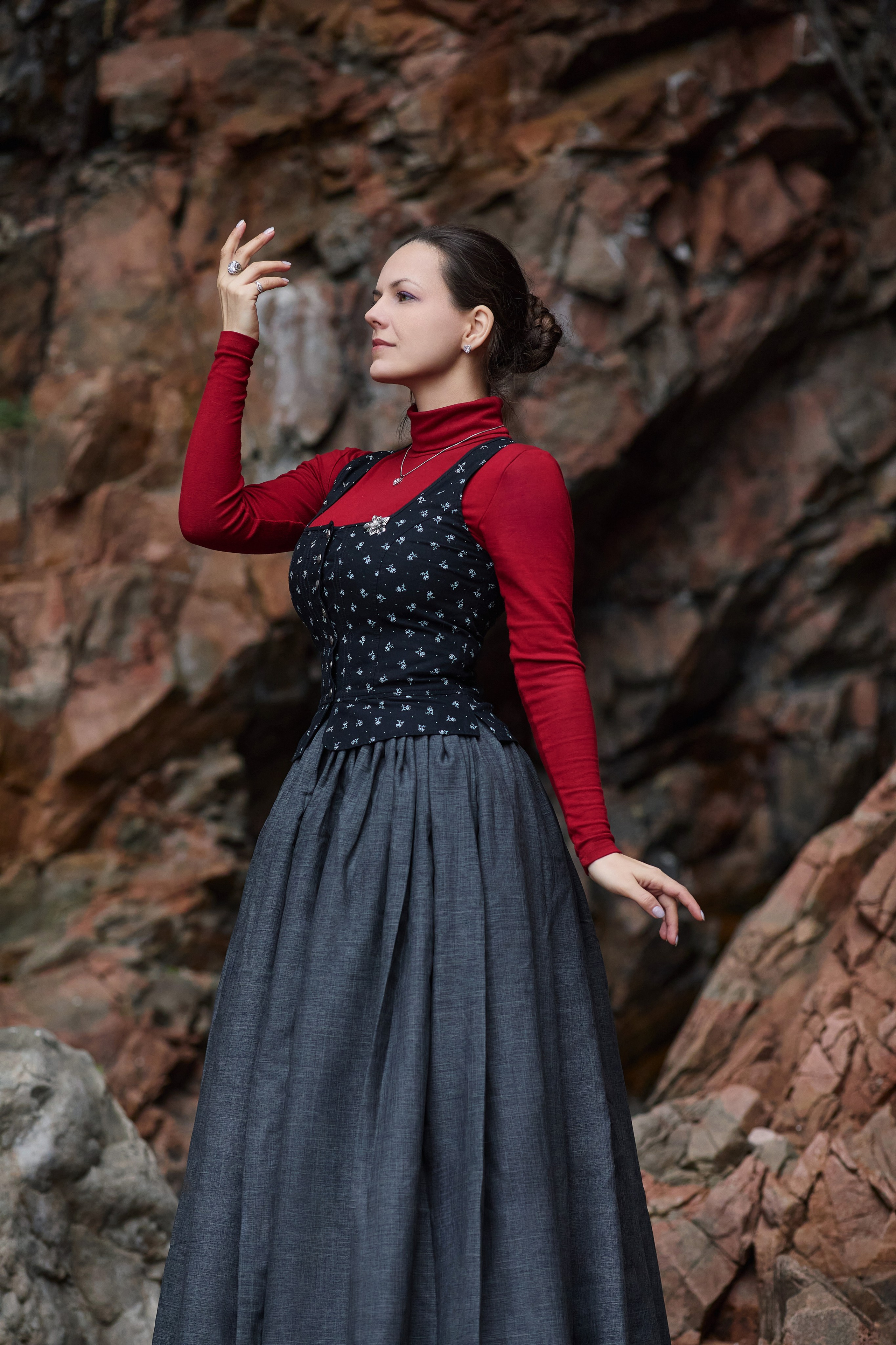 Девушка позирует в платье на фоне красных скал на побережье острова Шкота