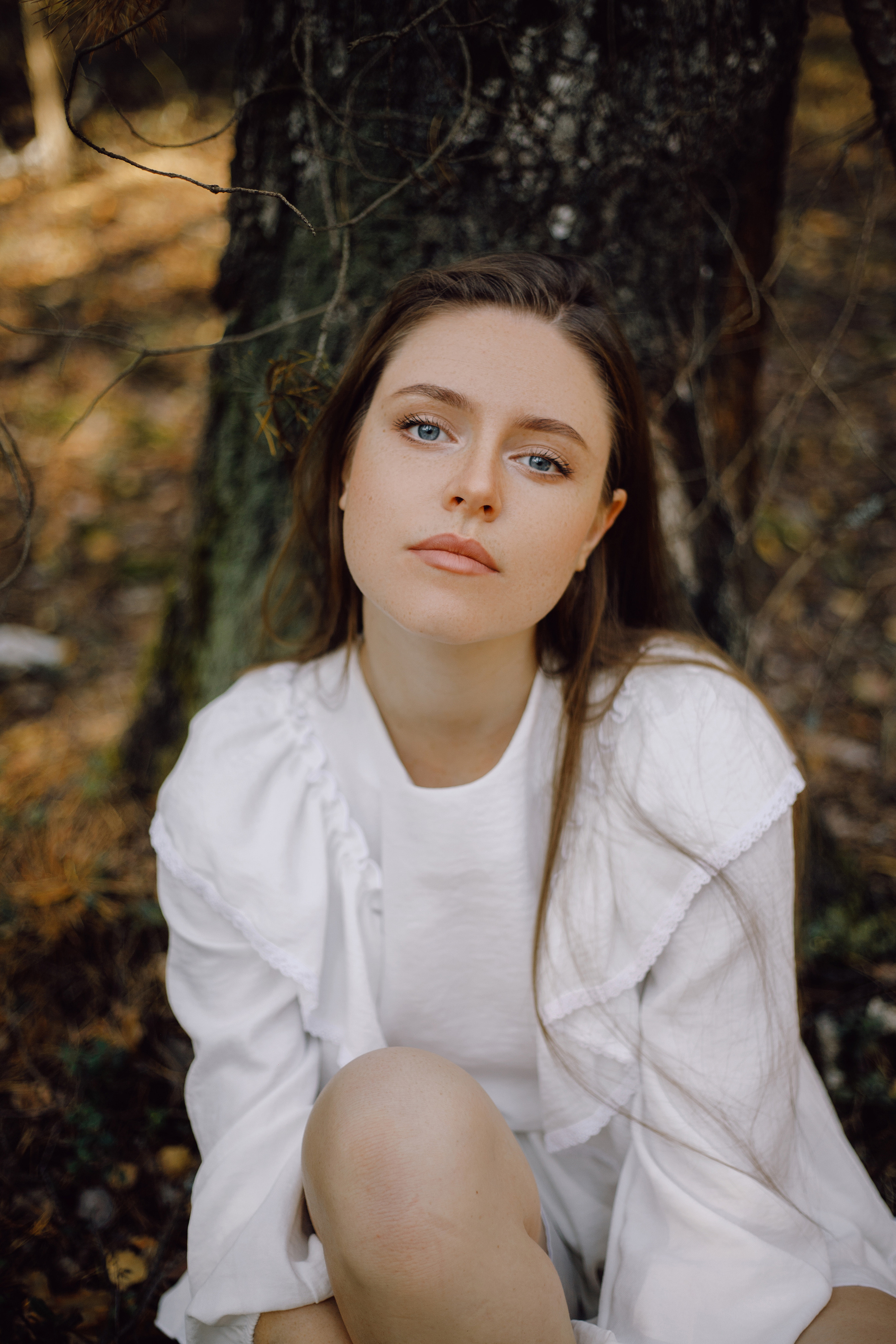 Девушка в белом платье среди деревьев в белом плате в осеннем лесу