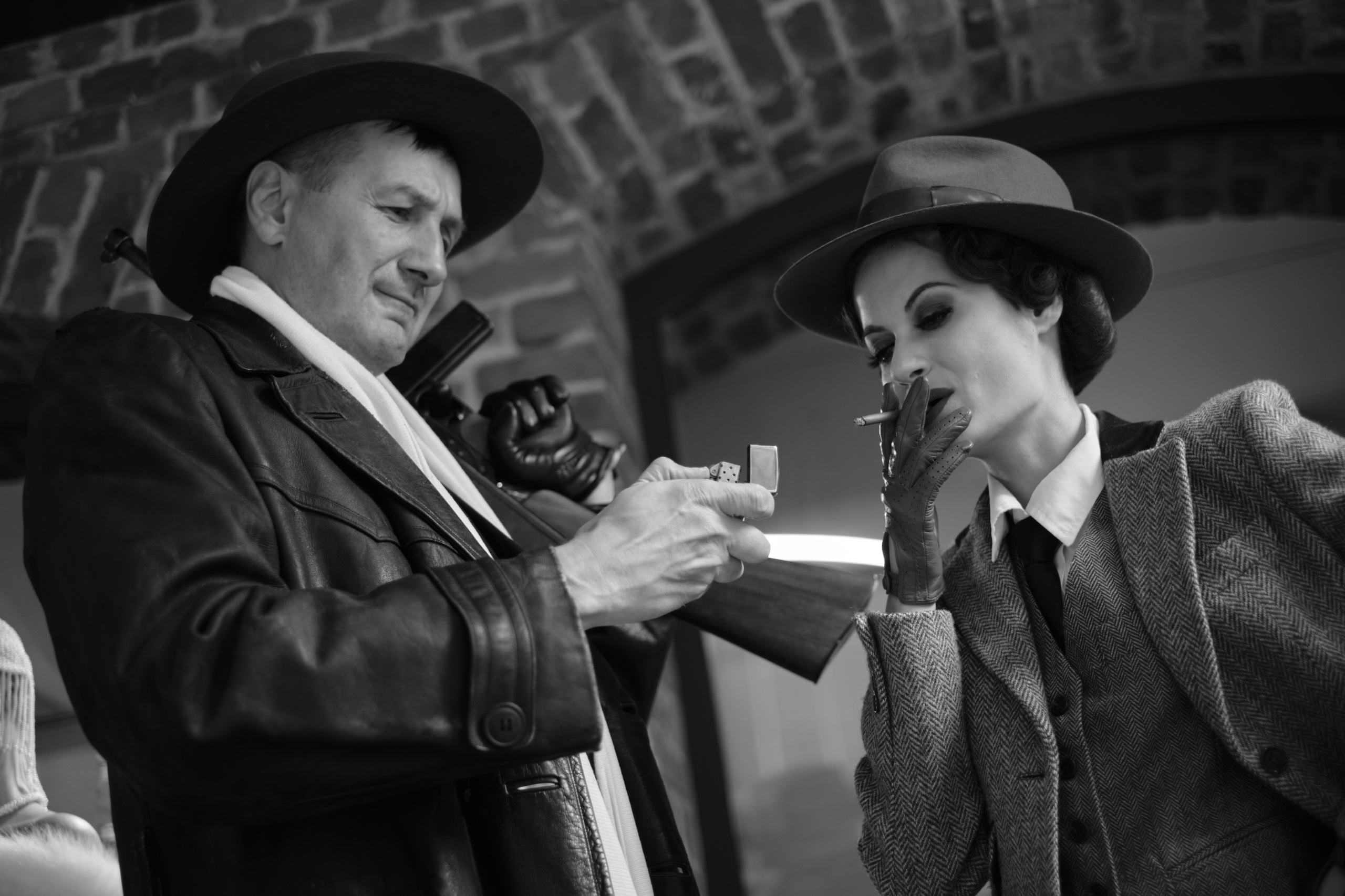 Мужчина в шляпе и пальто с автоматом Томсона дает прикурить девушке Чикаго 1930