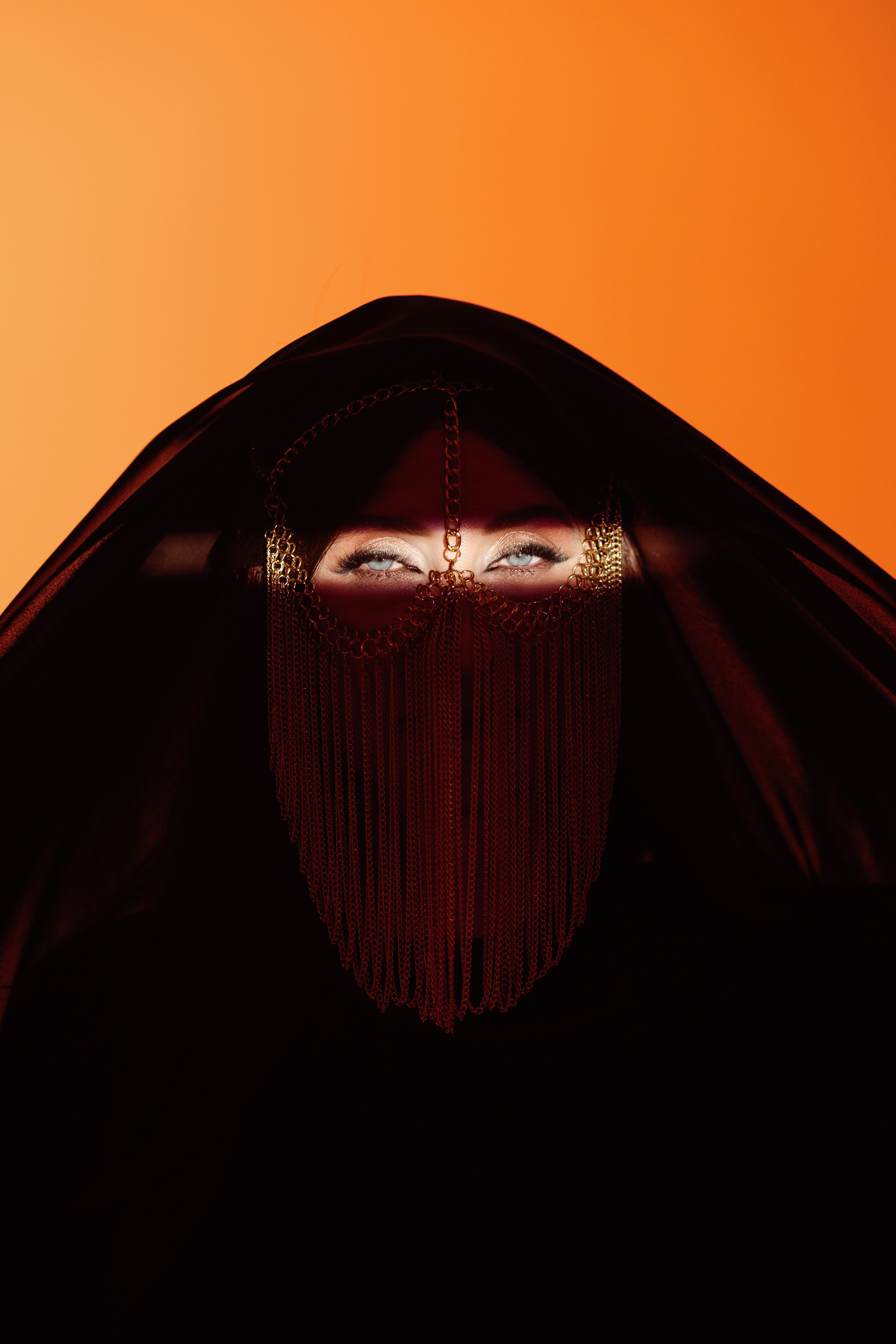 На фотографии изображена девушка в хиджабе в сутдии, лучом света выделены глаза, фотосессия в восточном стиле