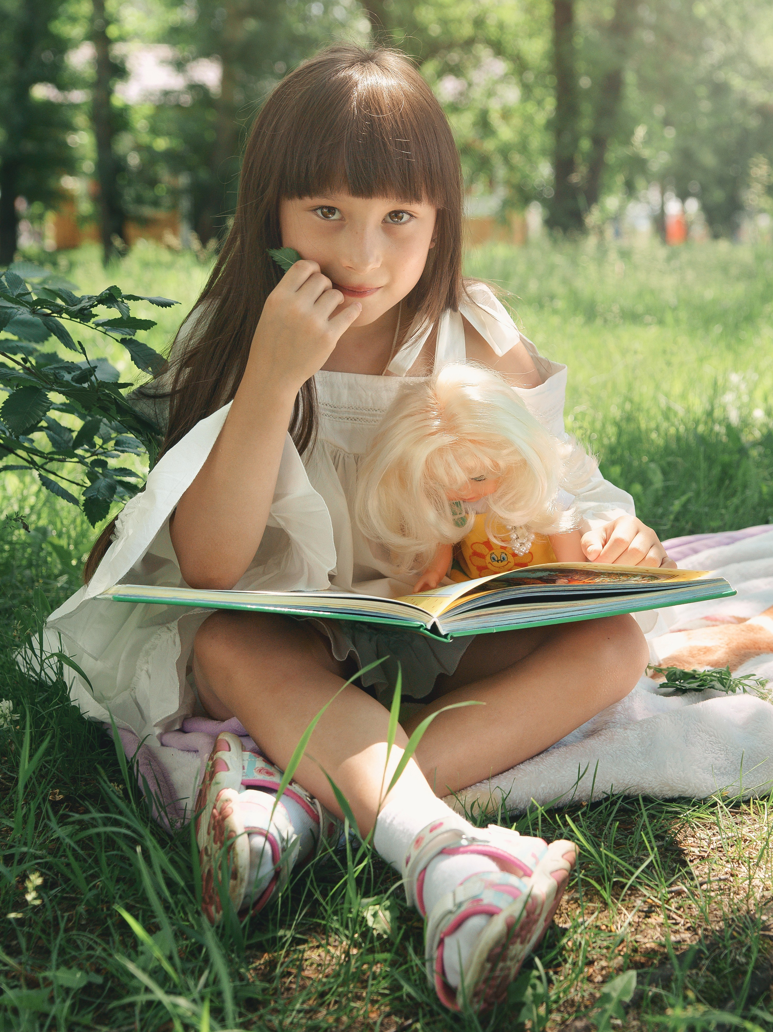Детская фотосессия летом - девочка на траве читает книгу