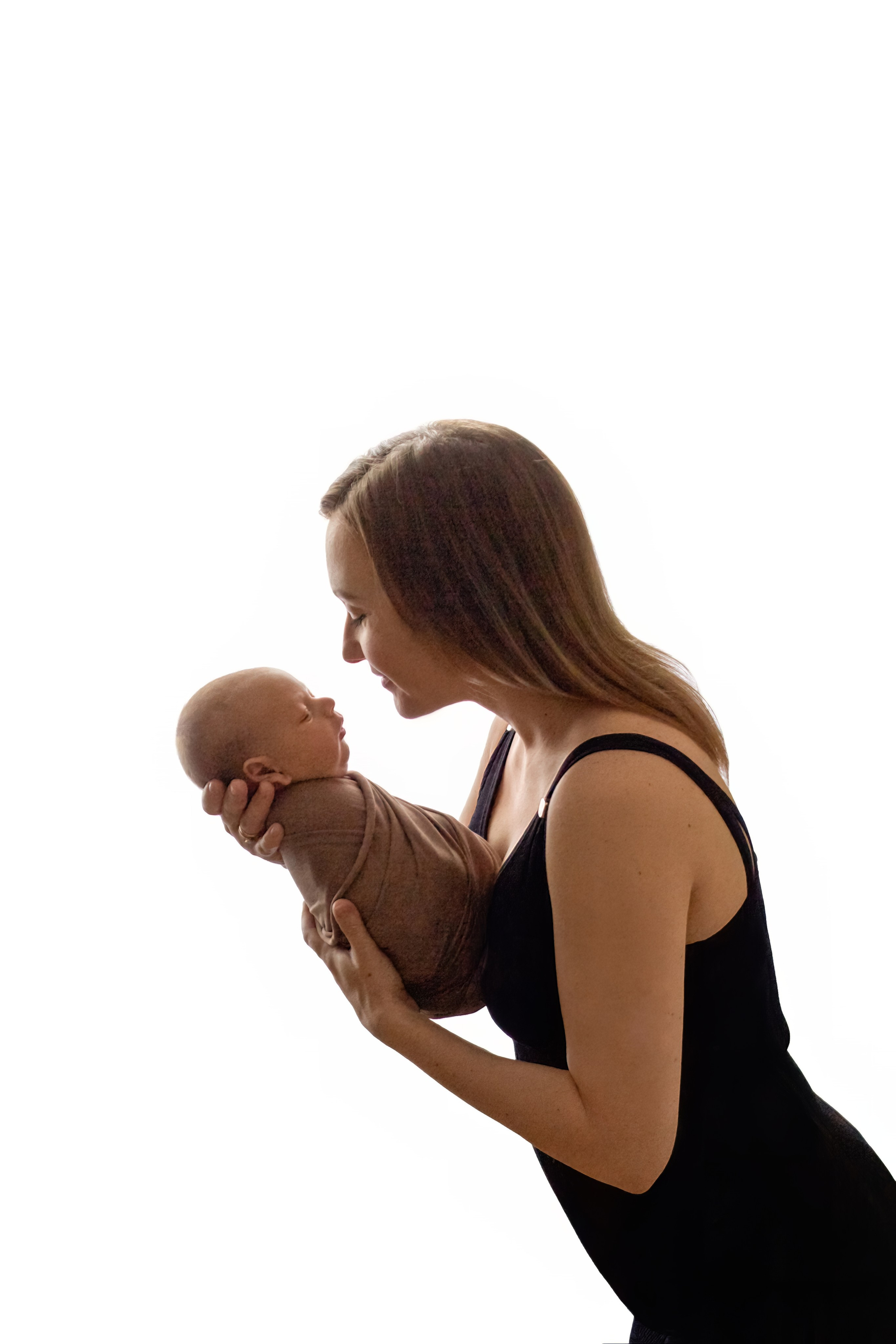 портрет молодой мамы в черном платье на лямочках с укутанным в бежевую ткань малышом на руках на белом фоне