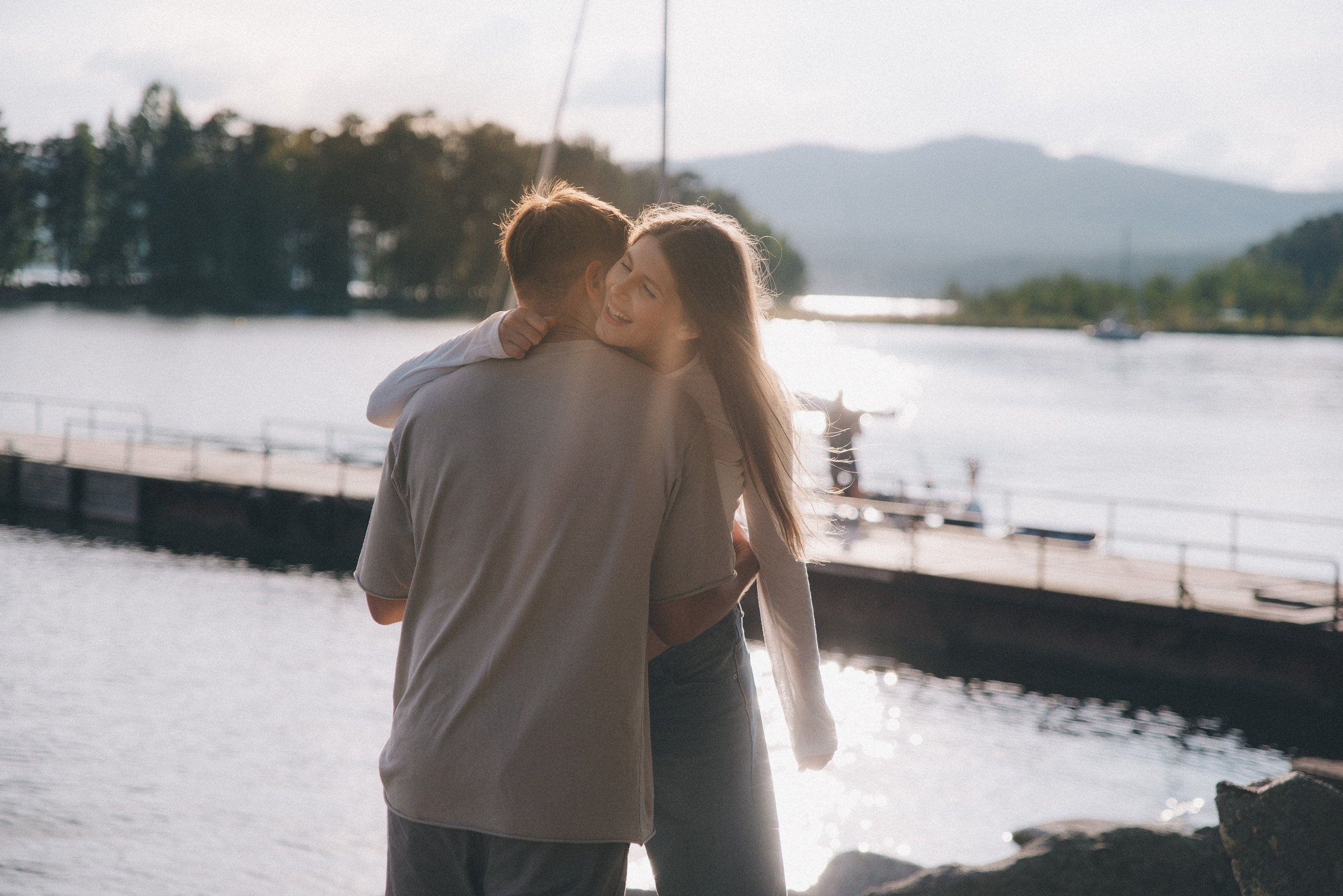 парень и девушка обнимаются на берегу озера в яхт клубе