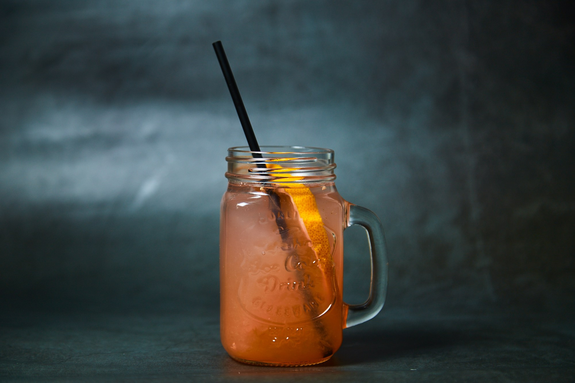 Фотосъёмка еды — апельсиновый лимонад в бокале с трубочкой.