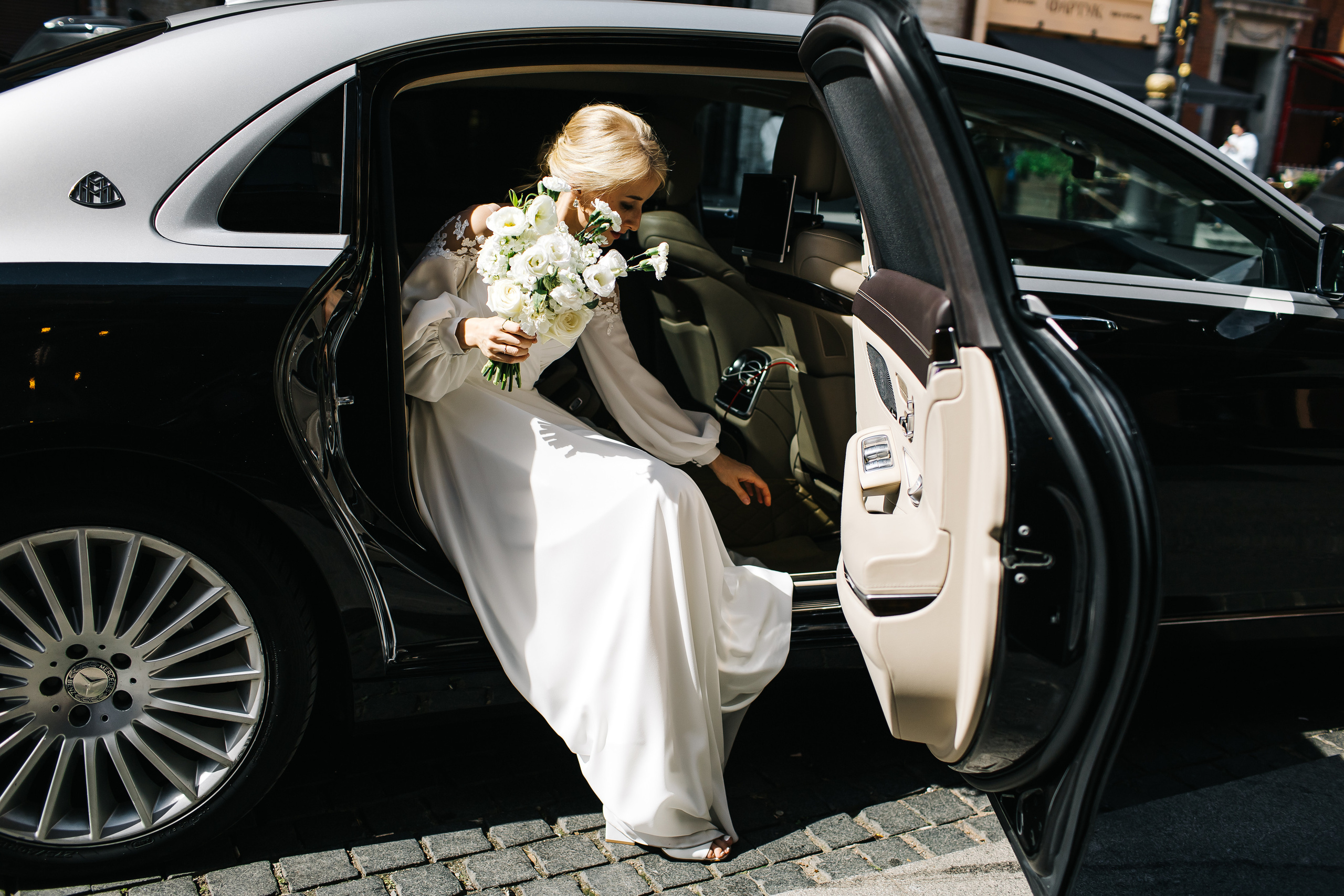 Невеста садится в свадебный лимузин