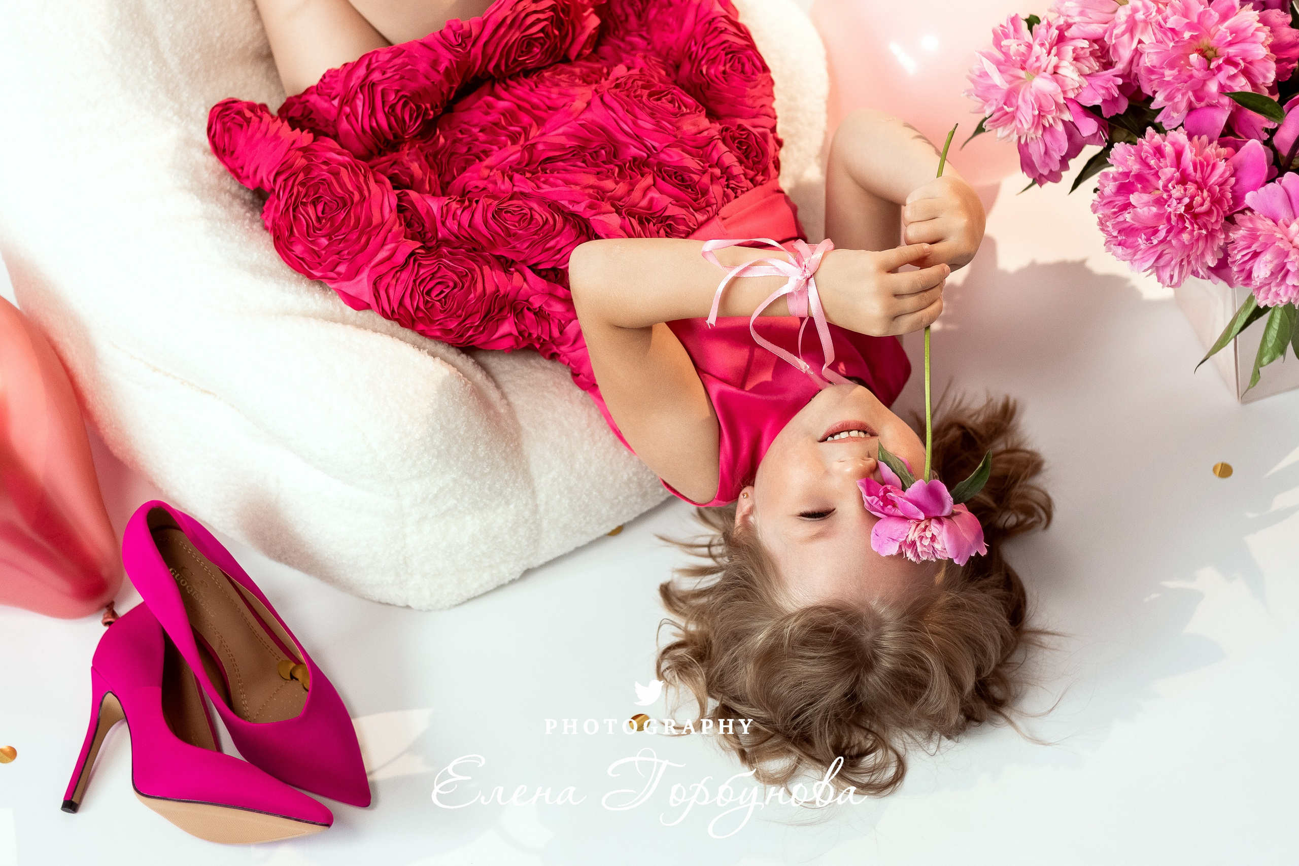 девочка модница в розовом с пионами на кресле вниз головой на фотосессии в студии