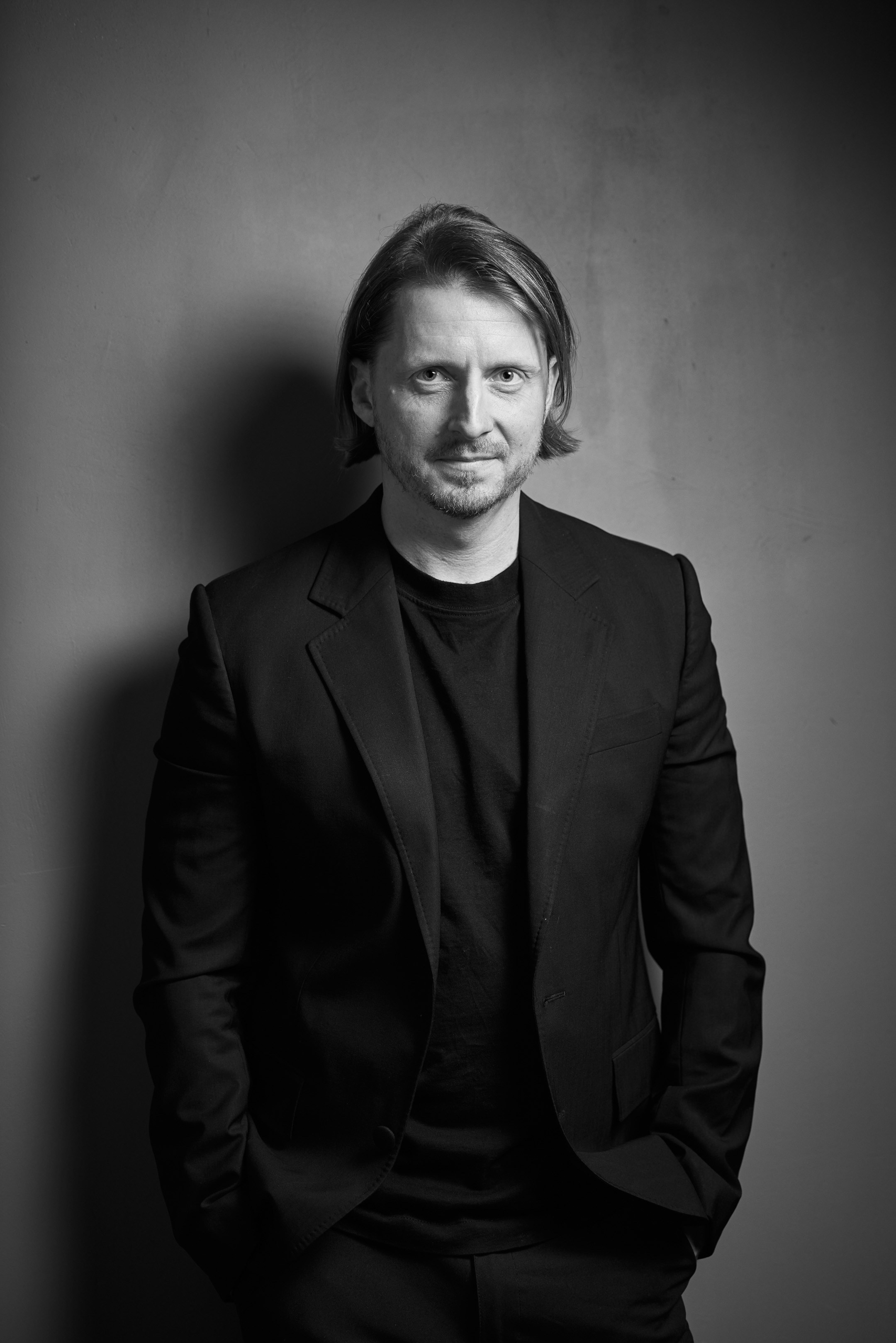 Black and white business portrait of a confident man in a suit on a dark studio background