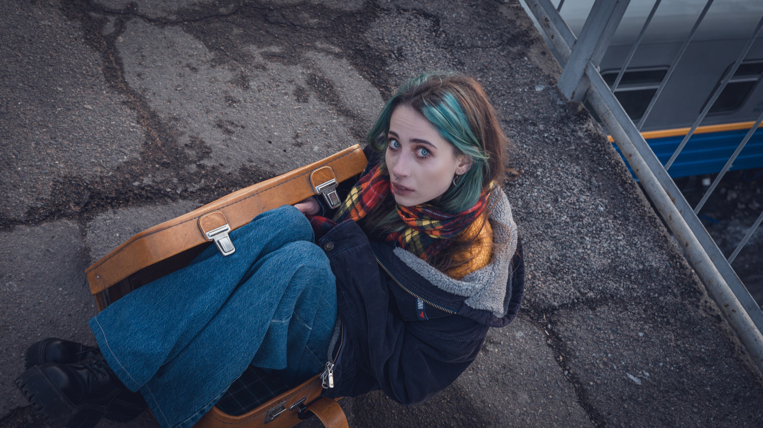 Съёмка на мосту: модель сидит у перил с чемоданом