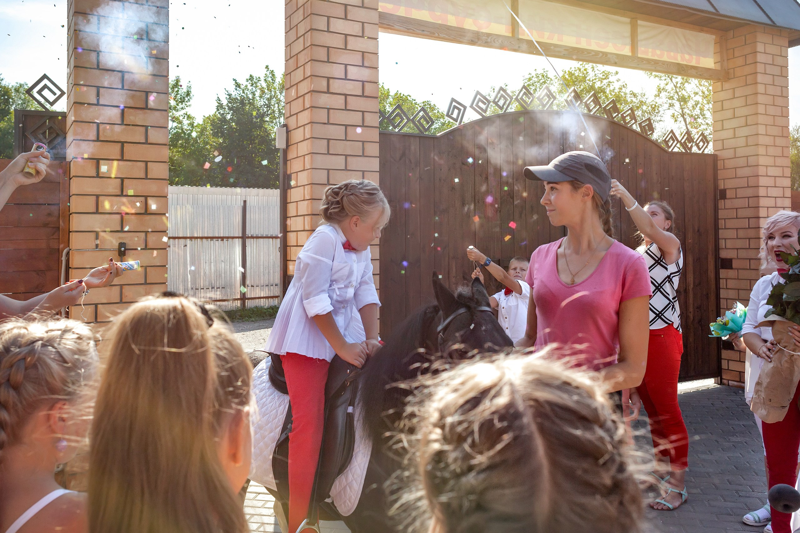 Девочка верхом на пони въезжает во двор кафе.