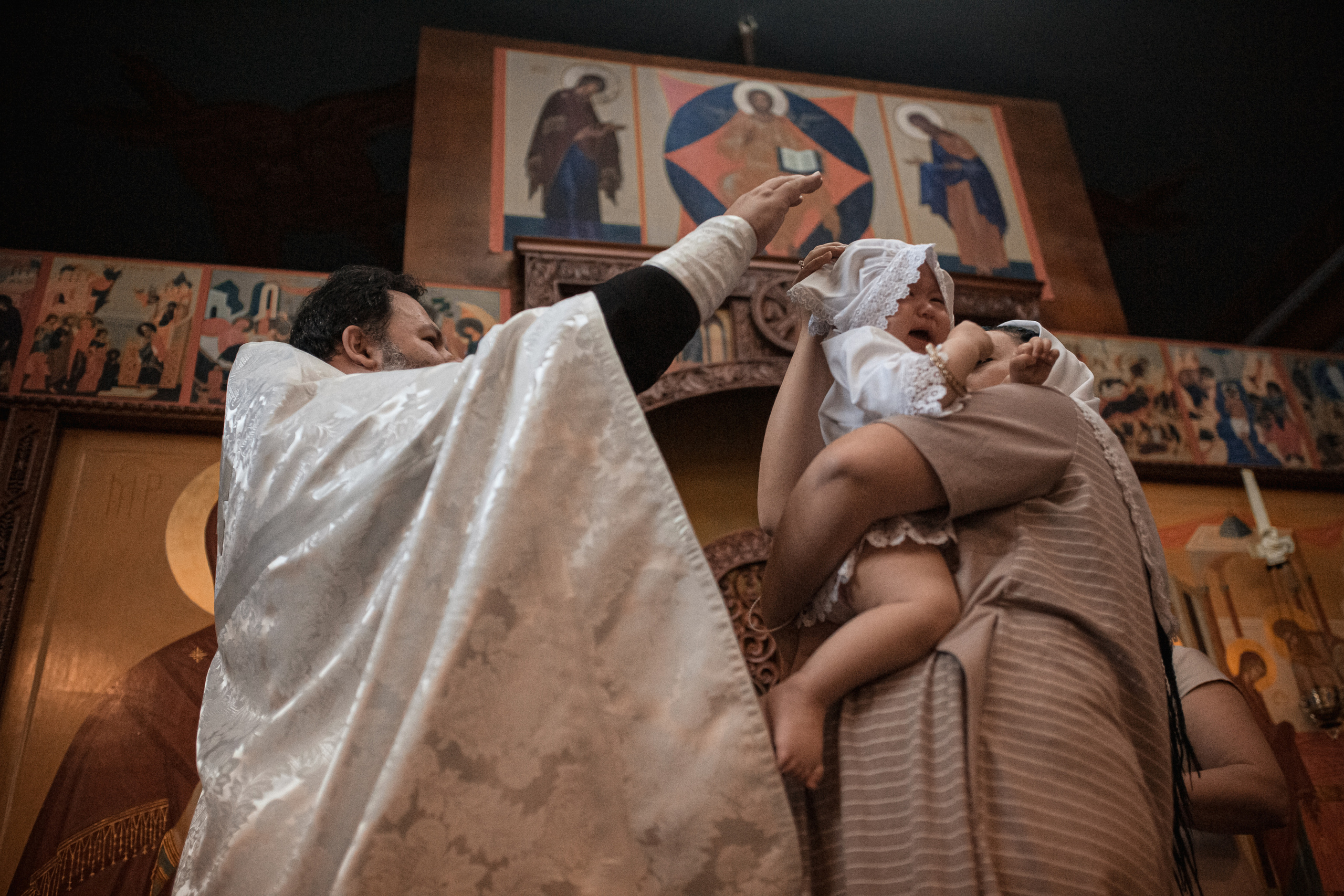 священник благословляет ребенка после совершения таинства крещения в Ташкенте