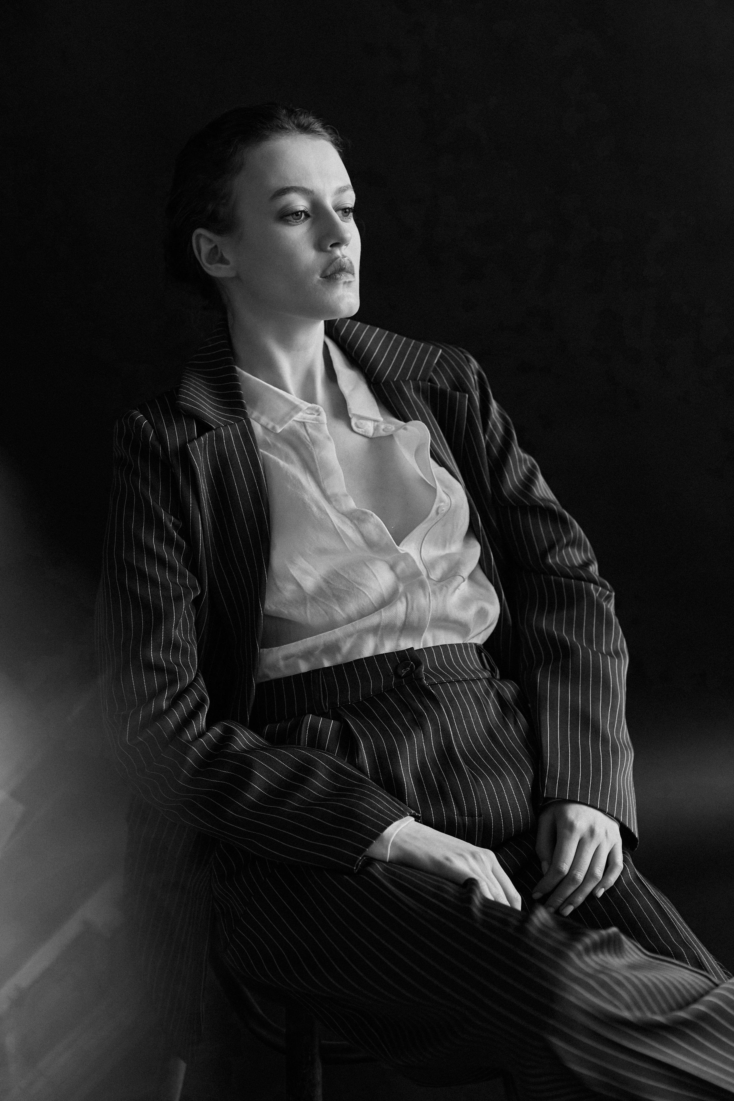 Фотограф в Москве. Студия. Студийный портрет. Девушка в пиджаке. Девушка на стуле на черном фоне. Красивая девушка в мужском костюме. Женский портрет. Черно-белое фото.