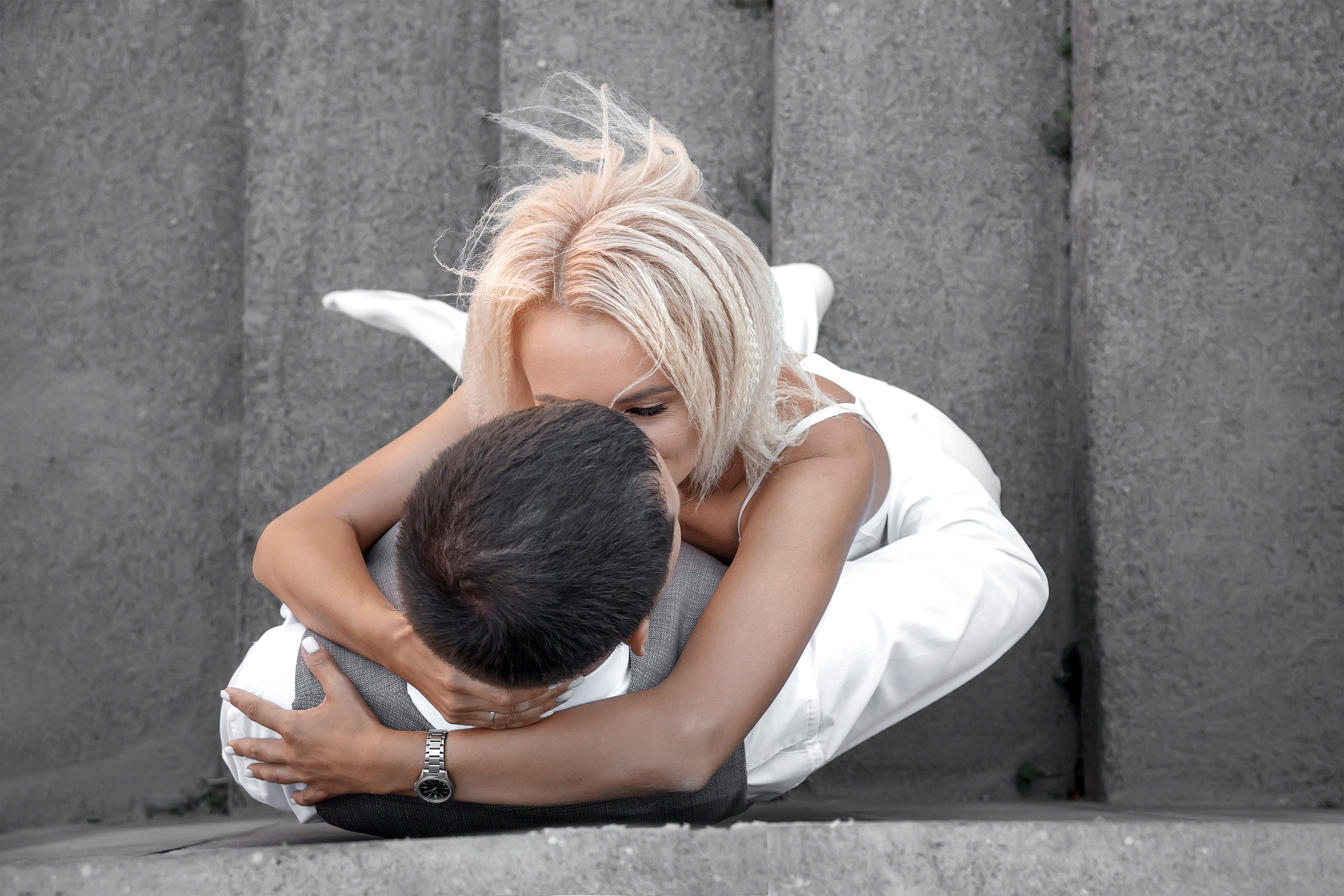 Жених и невеста обнимаются у серой стены на лестнице в городе, вид сверху, фотограф Янкаускене Наталья