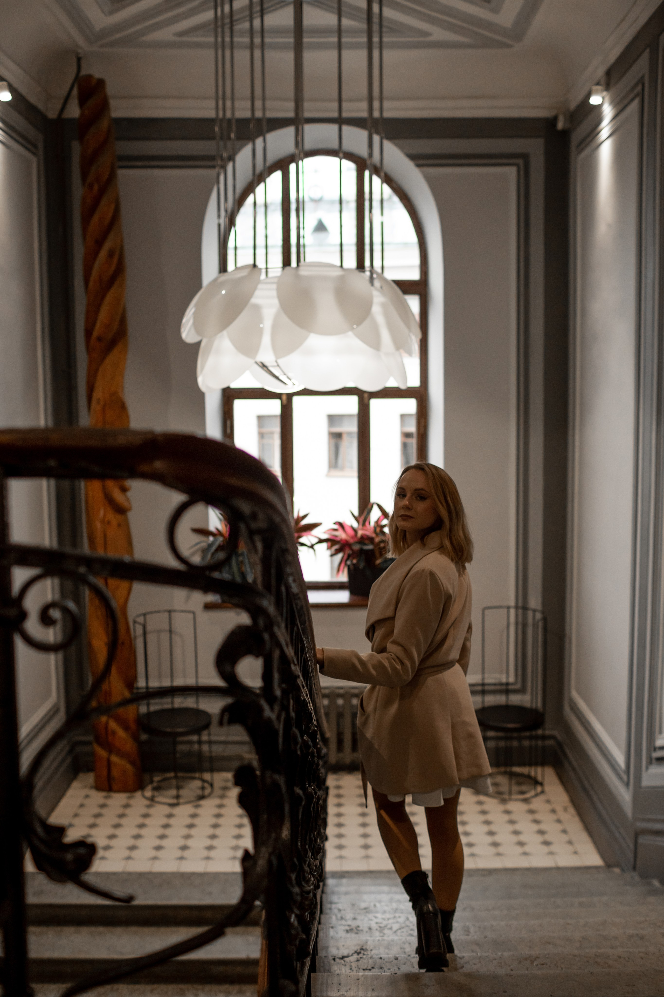 Молодая блондинка фотографируется в красивой парадной с большим витражным окном.