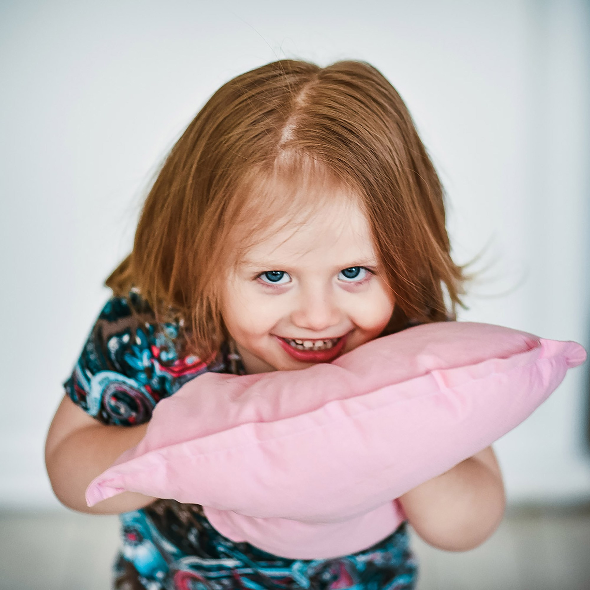 девочка играет с подушкой