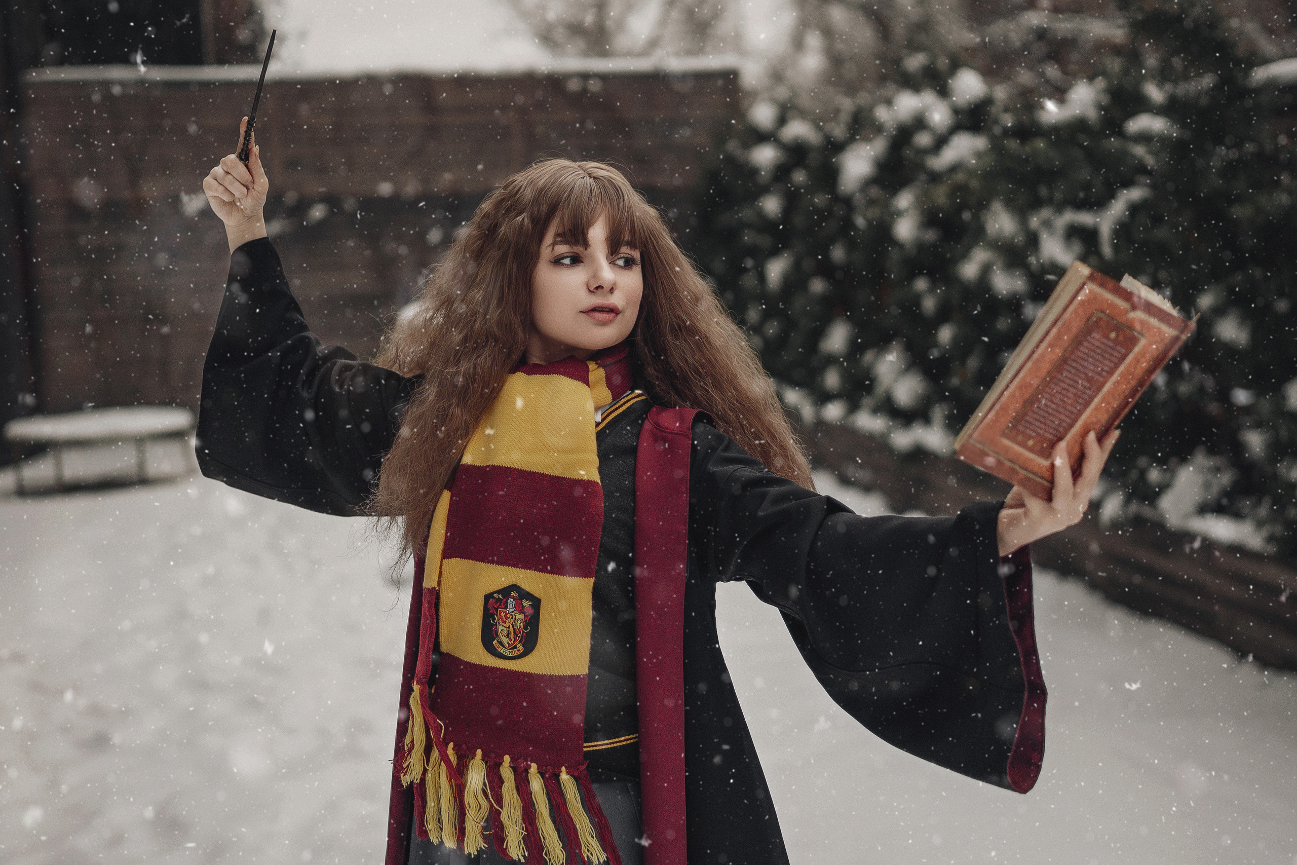 Девушка в образе Гермионы колдует магию с книги.