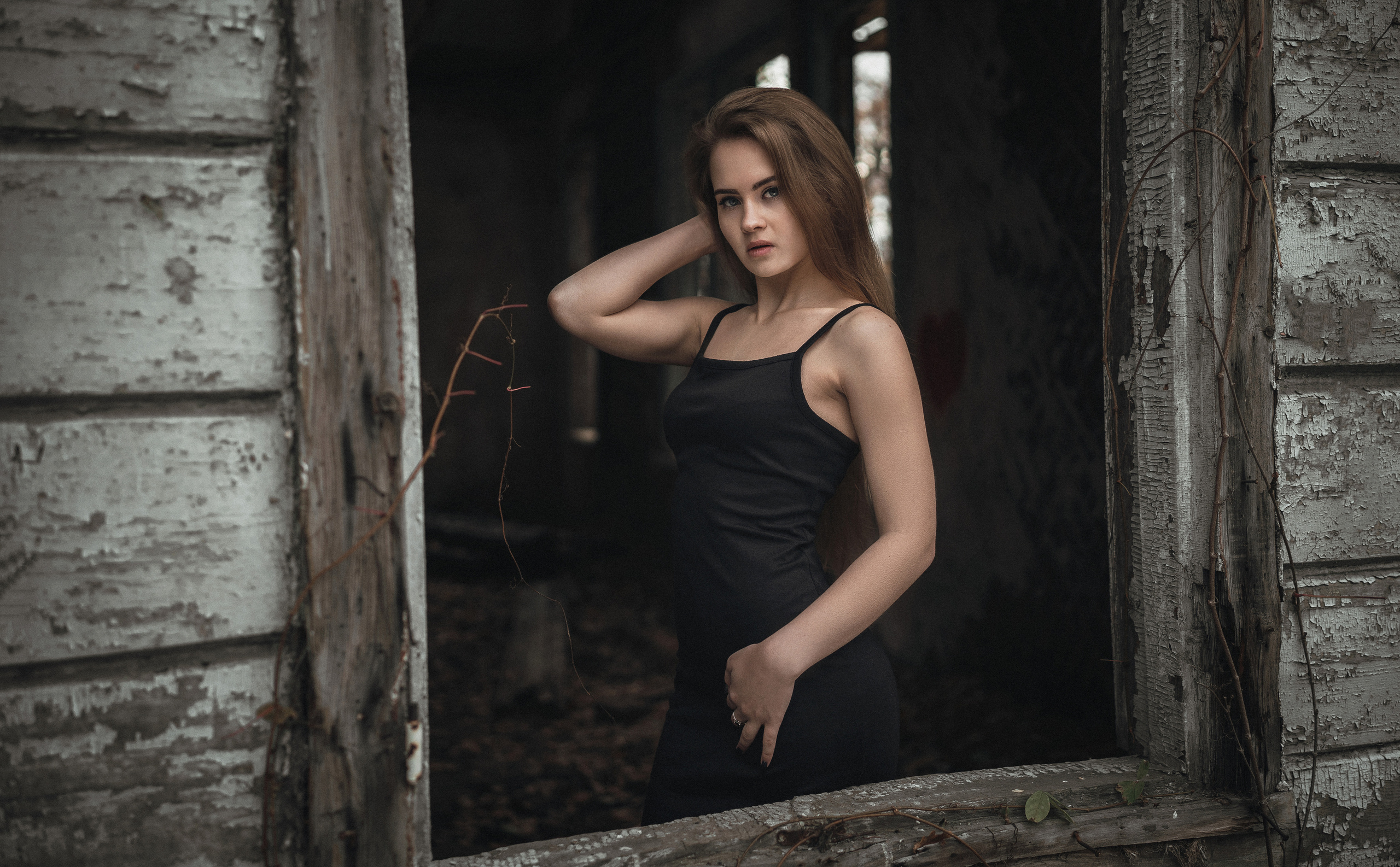 Девушка в черном платье стоит около окна. Автор: Роман Яковенко