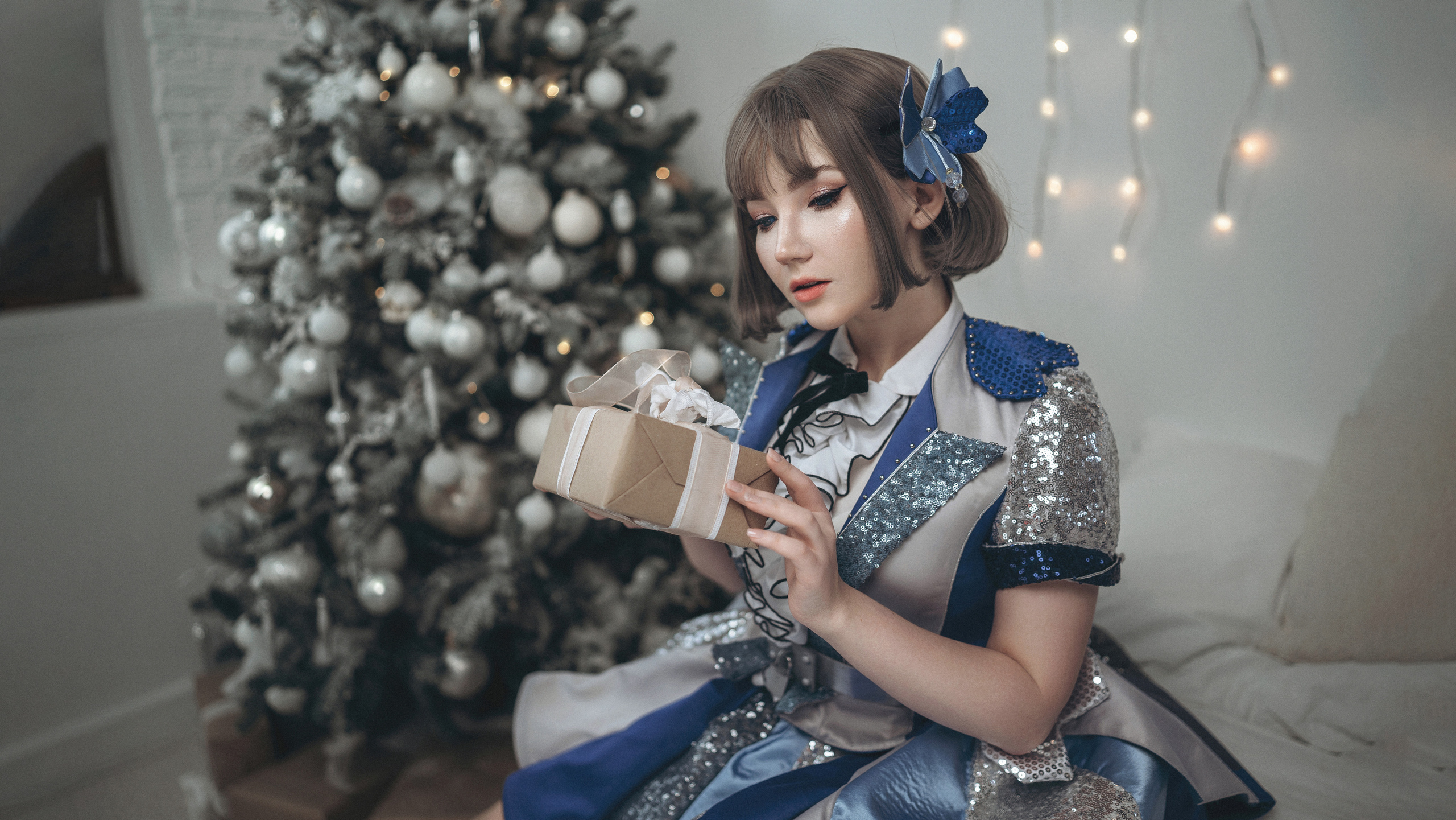 Девушка в синем платье держит подарок в руках.