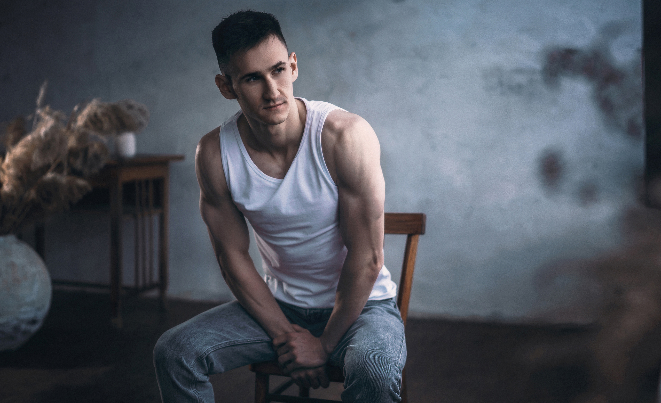Парень в белой майке сидит на стуле в студии. Фотограф в городе Воронеже.