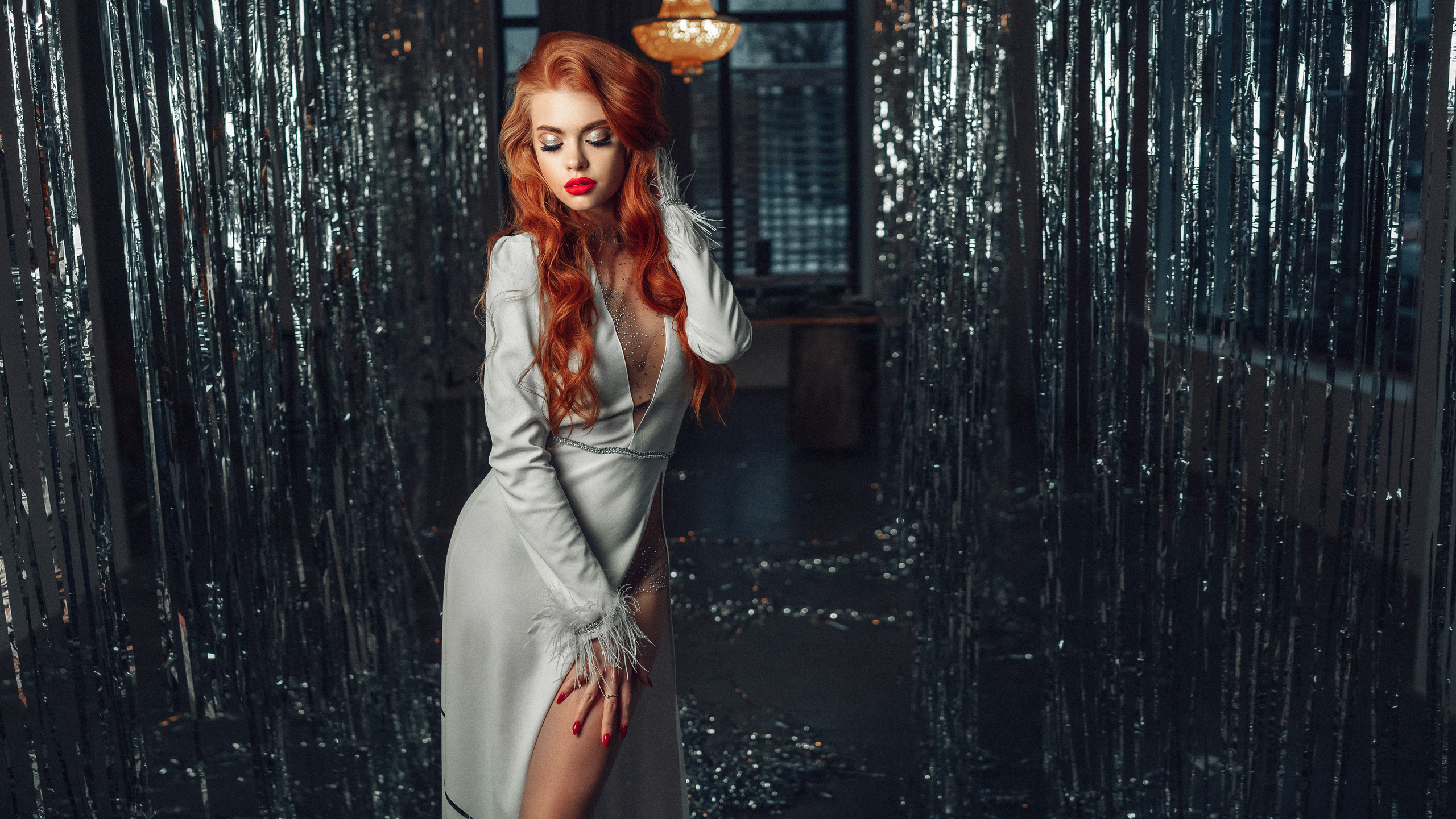 Девушка с рыжими волосами в белом платье  в студии с новогодней мишурой держит волосы. Автор: Роман Яковенко