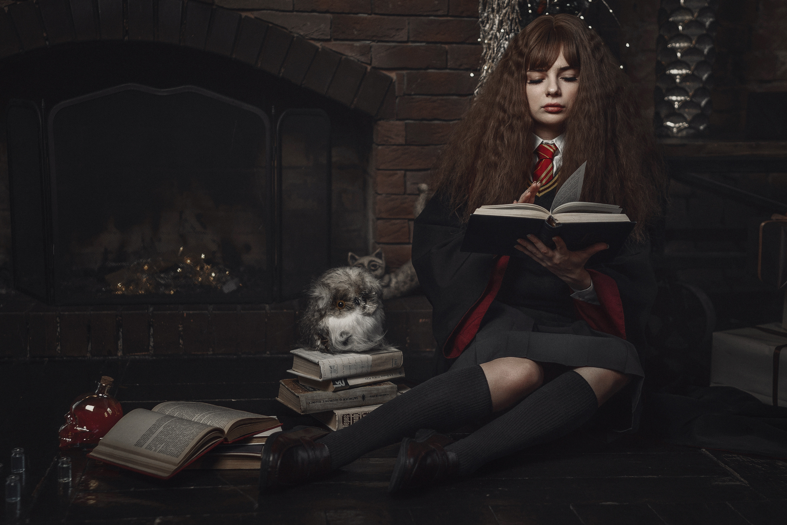 Девушка в образе Гермионы читает книгу.