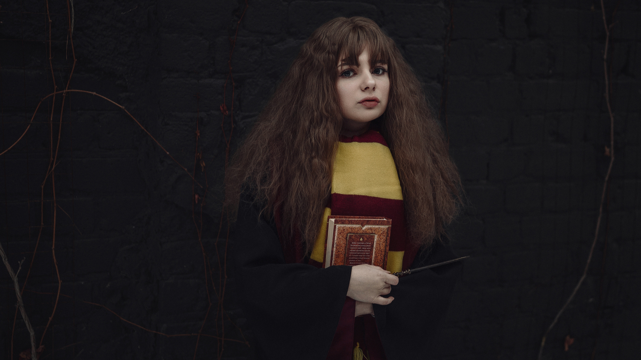 Девушка в образе Гермионы у черной стены.