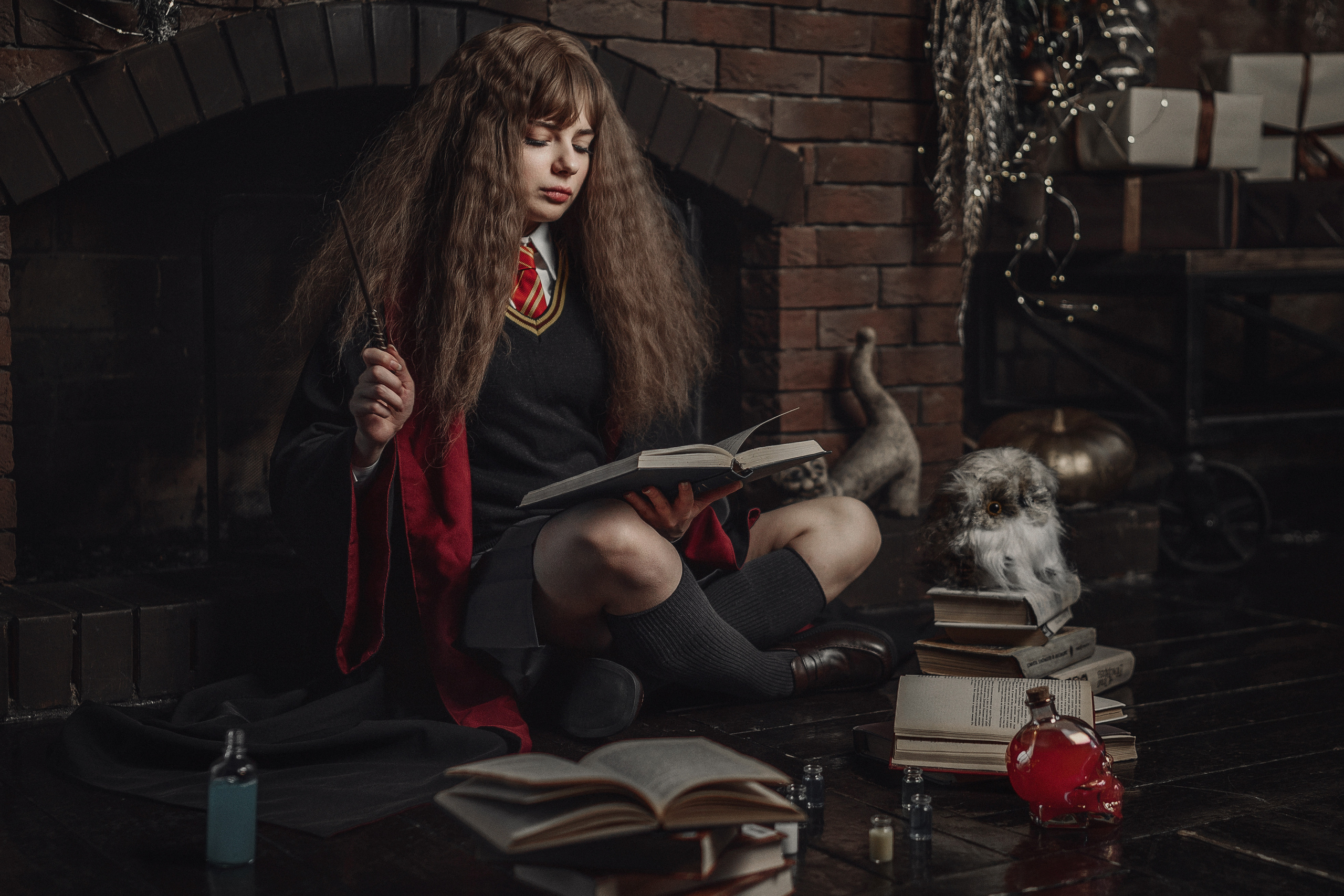 Девушка в образе Гермионы сидит у камина.