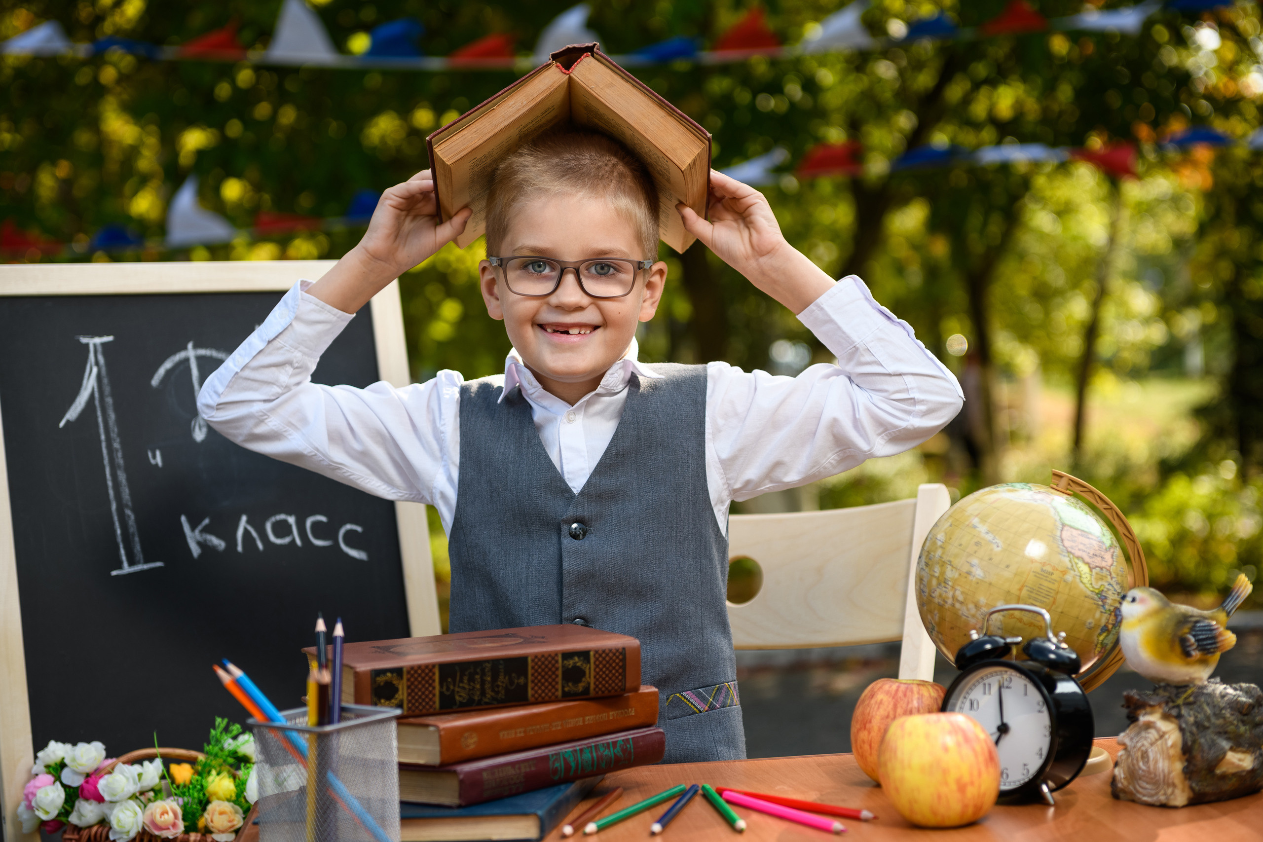 Первоклассник прикрыл голову раскрытой книгой, имитируя домик.