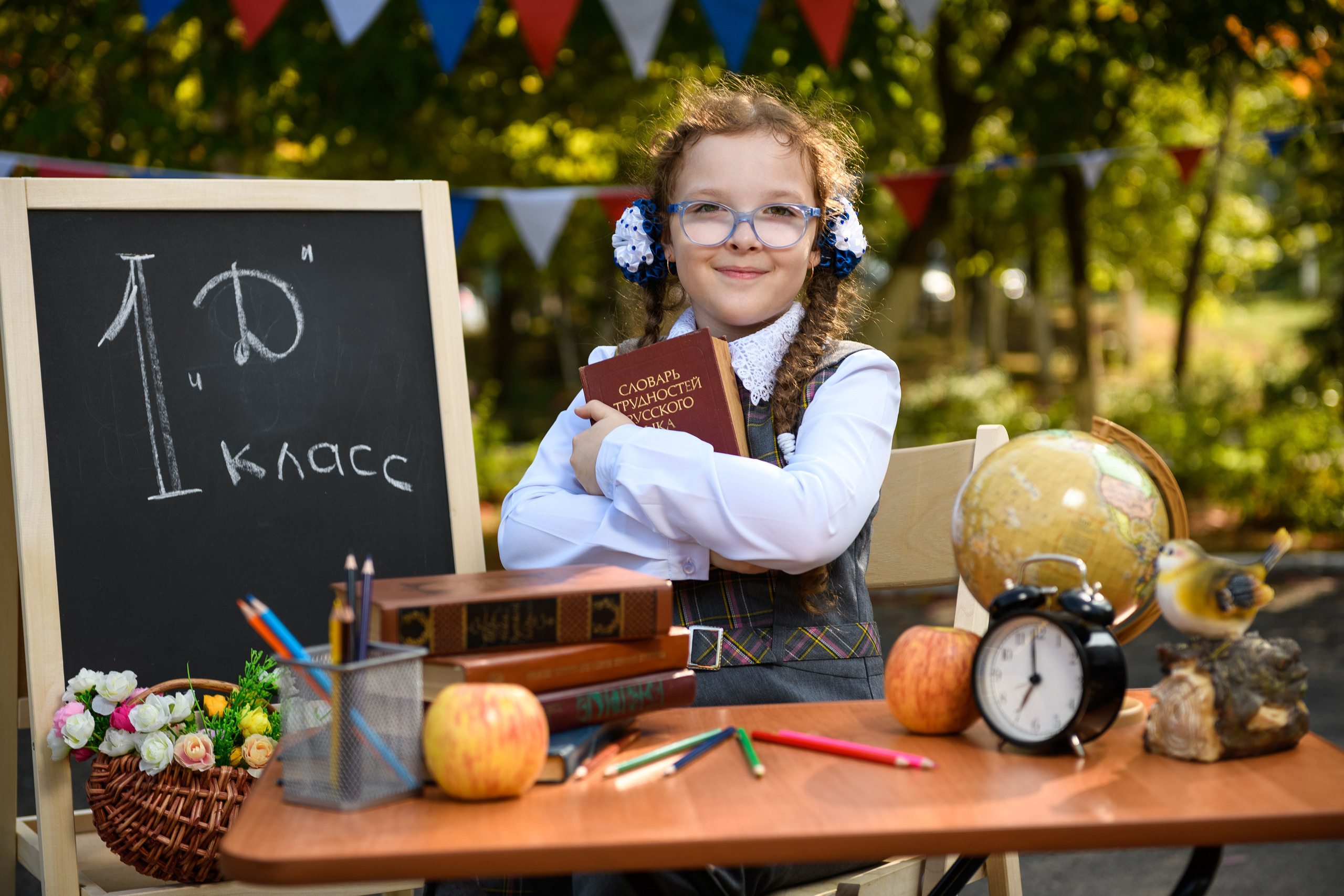 Первоклассница за партой обняв книгу.