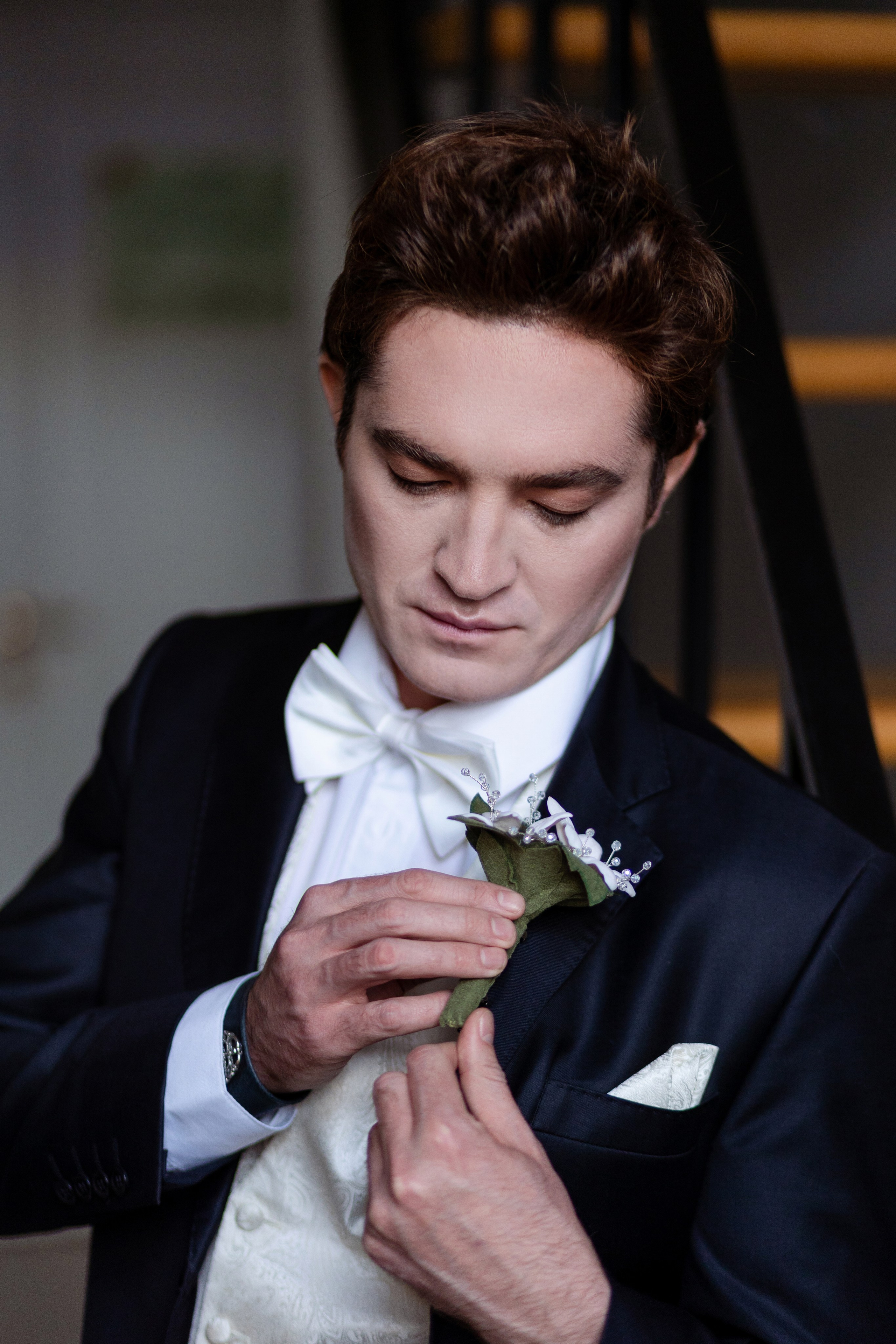 Жених поправляет букетик цветов в пиджаке.