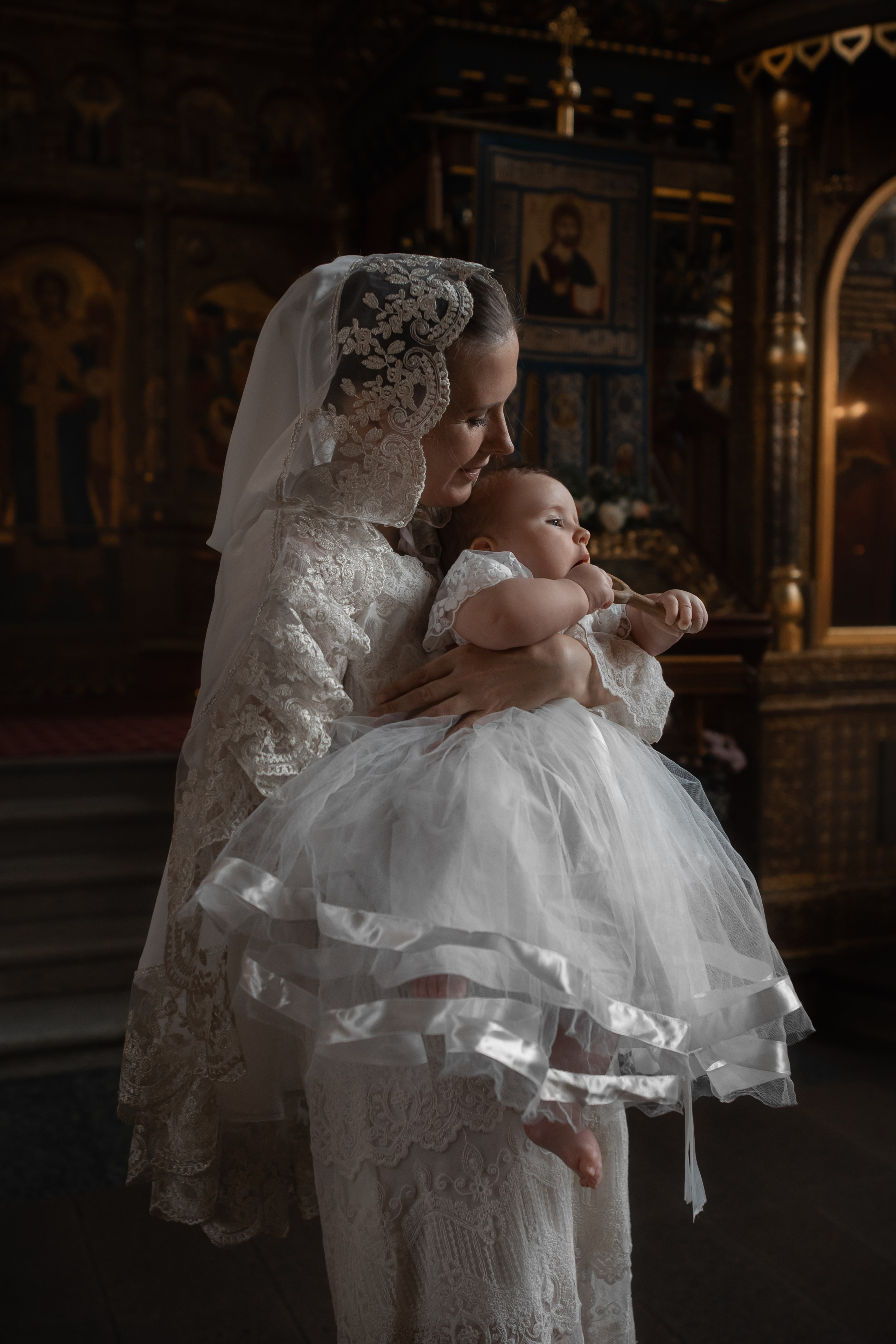 мама с дочкой в белых одеяниях в полумраке собора