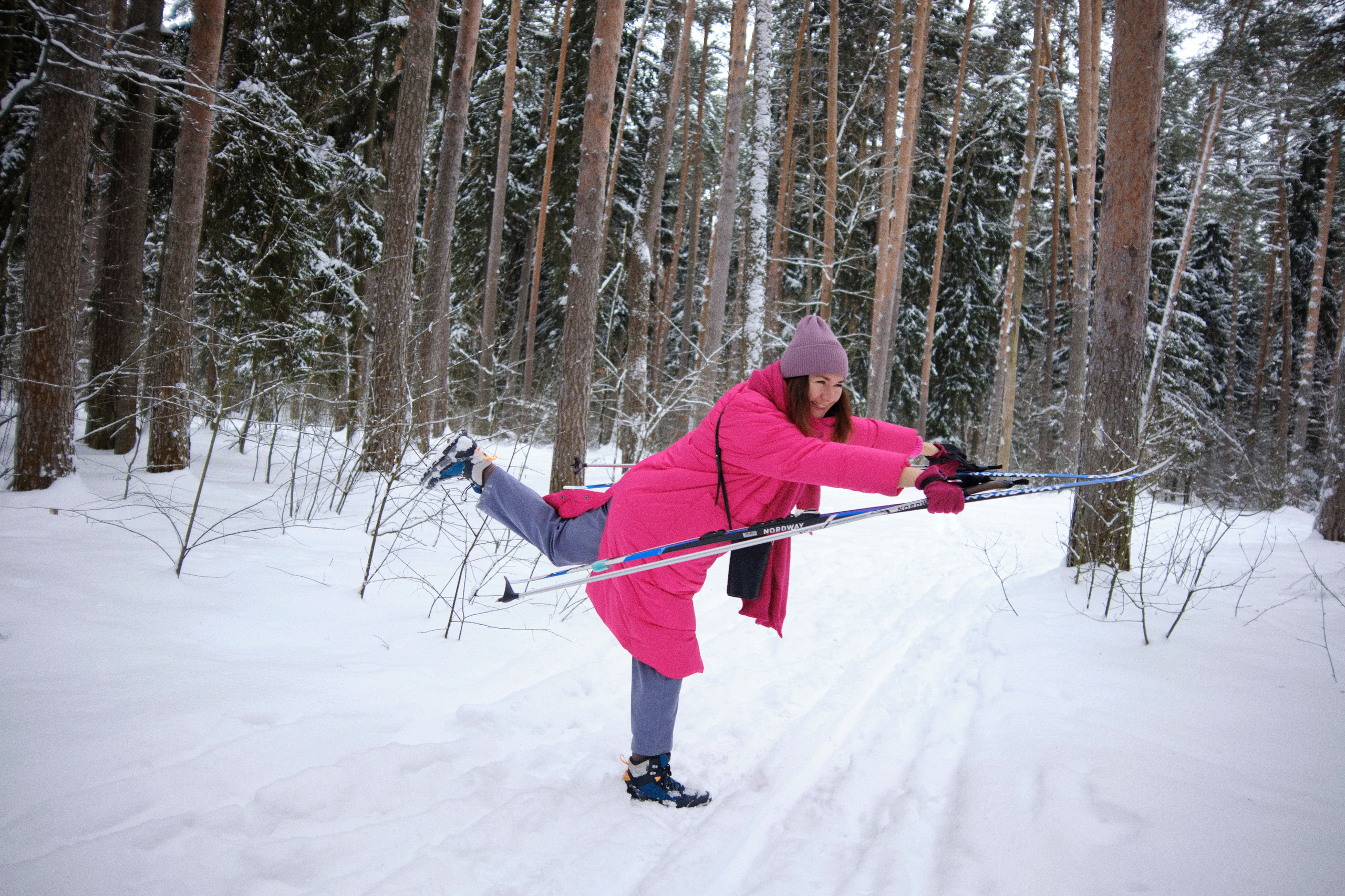 Женщина веселится с лыжами в зимнем лесу