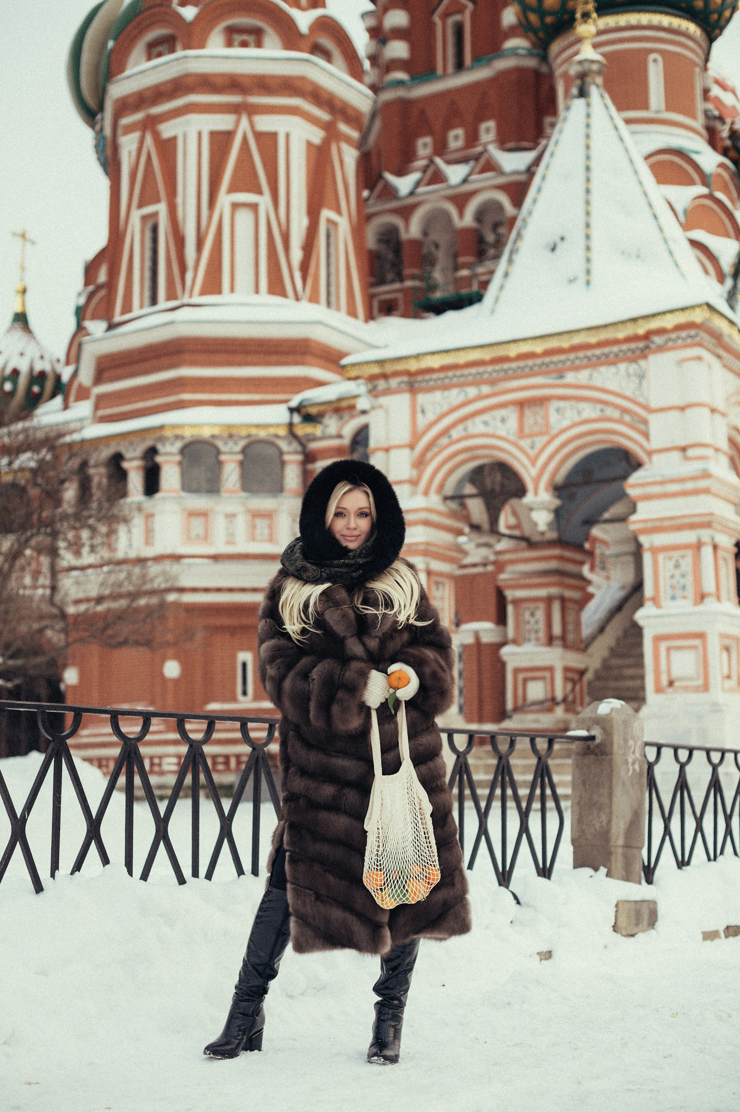 Девушка в стиле Russian girl  в полный рост на фоне храма Василия Блаженного на Красной площади в Москве с авоськой с мандаринами
