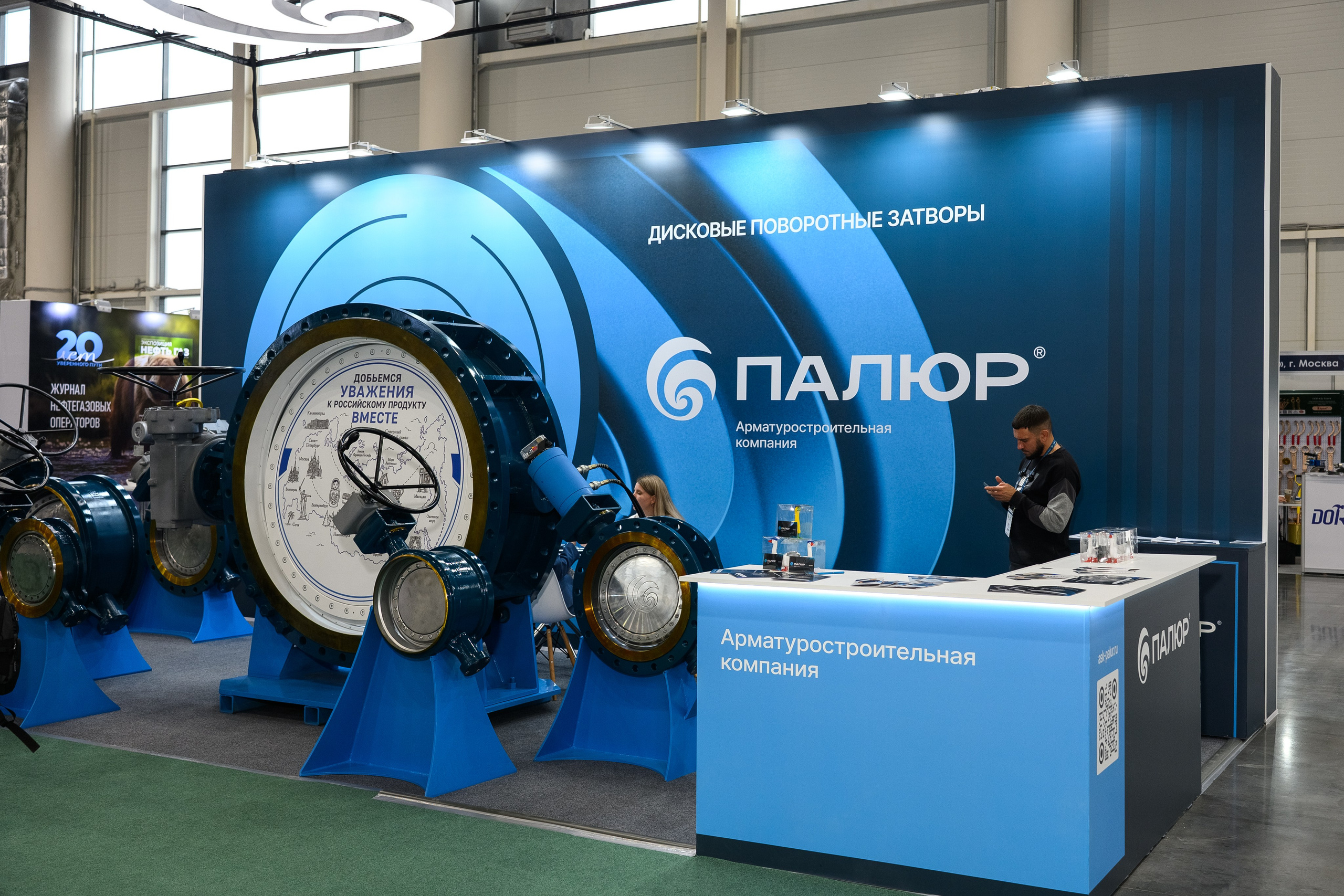 Фотография выставочного стенда нефтегазовой отрасли с промышленным оборудованием, техническими образцами и специалистами, снятая фотографом Алексеем Клейменовым в Казани