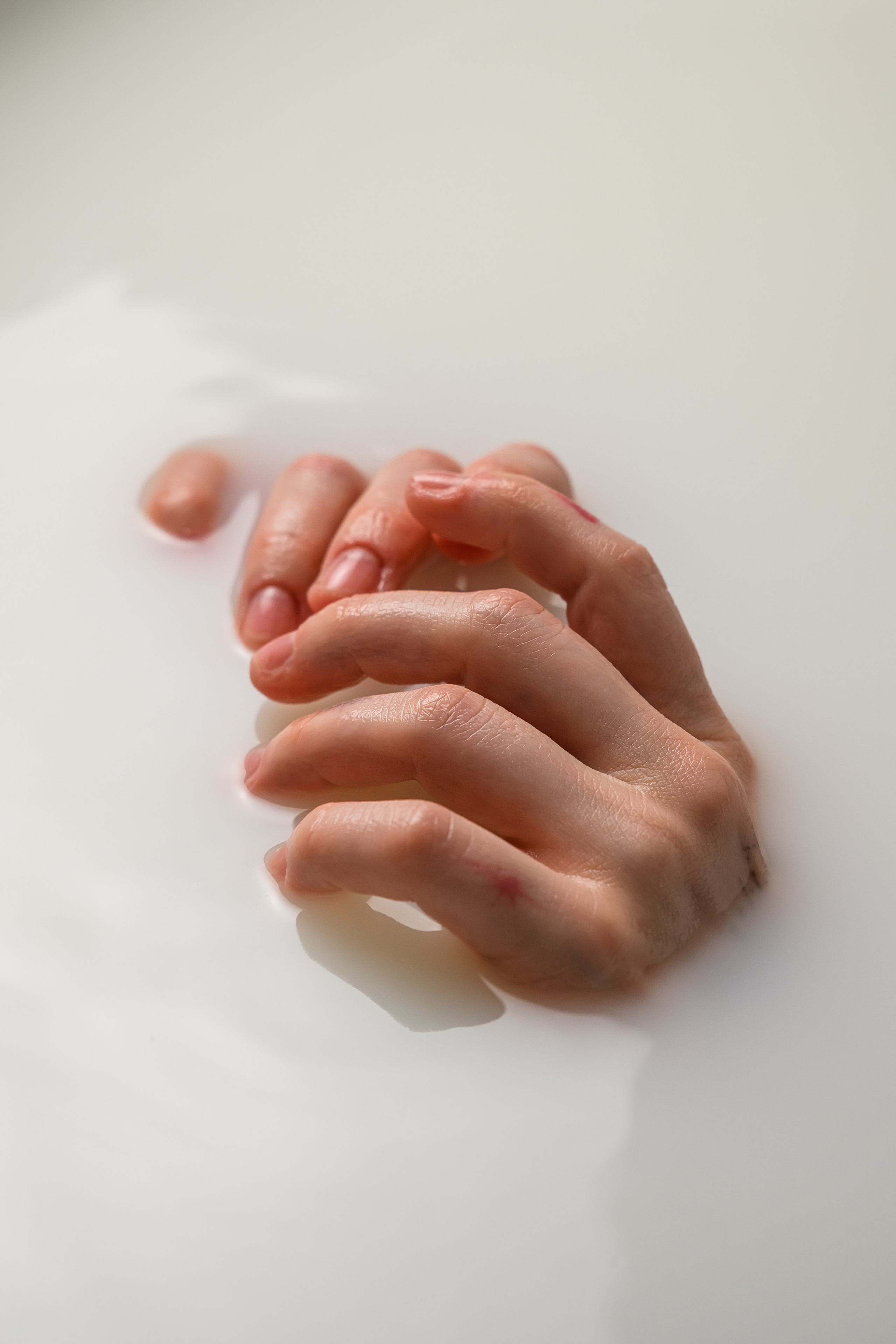 Ню-съемка Карины Ved.Nudes в молочной воде с графичным силуэтом, светлым фоном и минималистичной художественной эстетикой