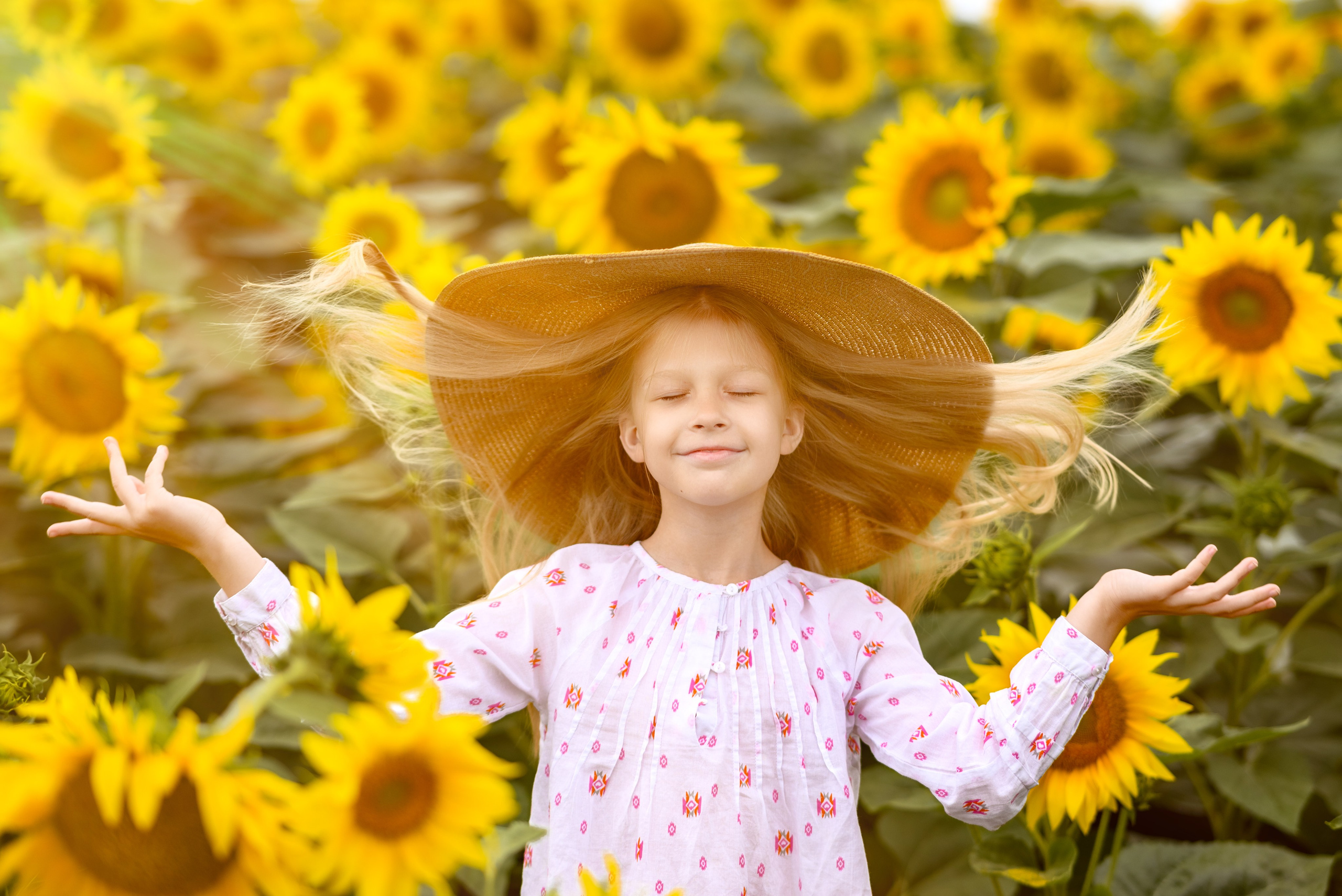 Детская фотосъемка на природе — девочка в шляпе среди подсолнухов
