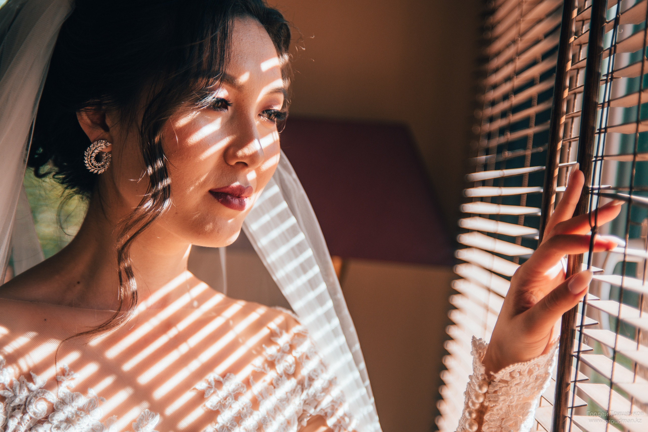 Невеста смотрит в окно сквозь жалюзи