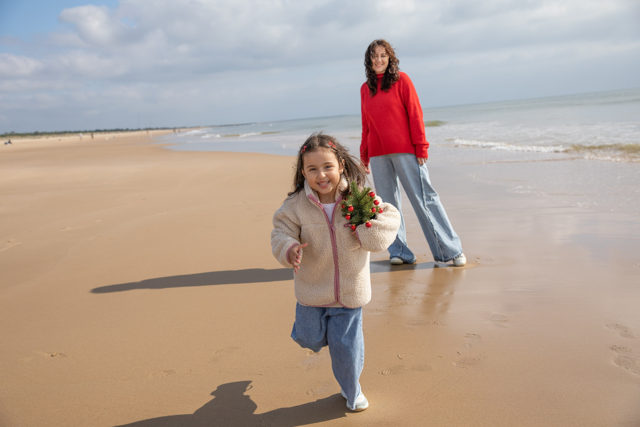 Mum, dad, and daughter laughing together as the waves touch their feet