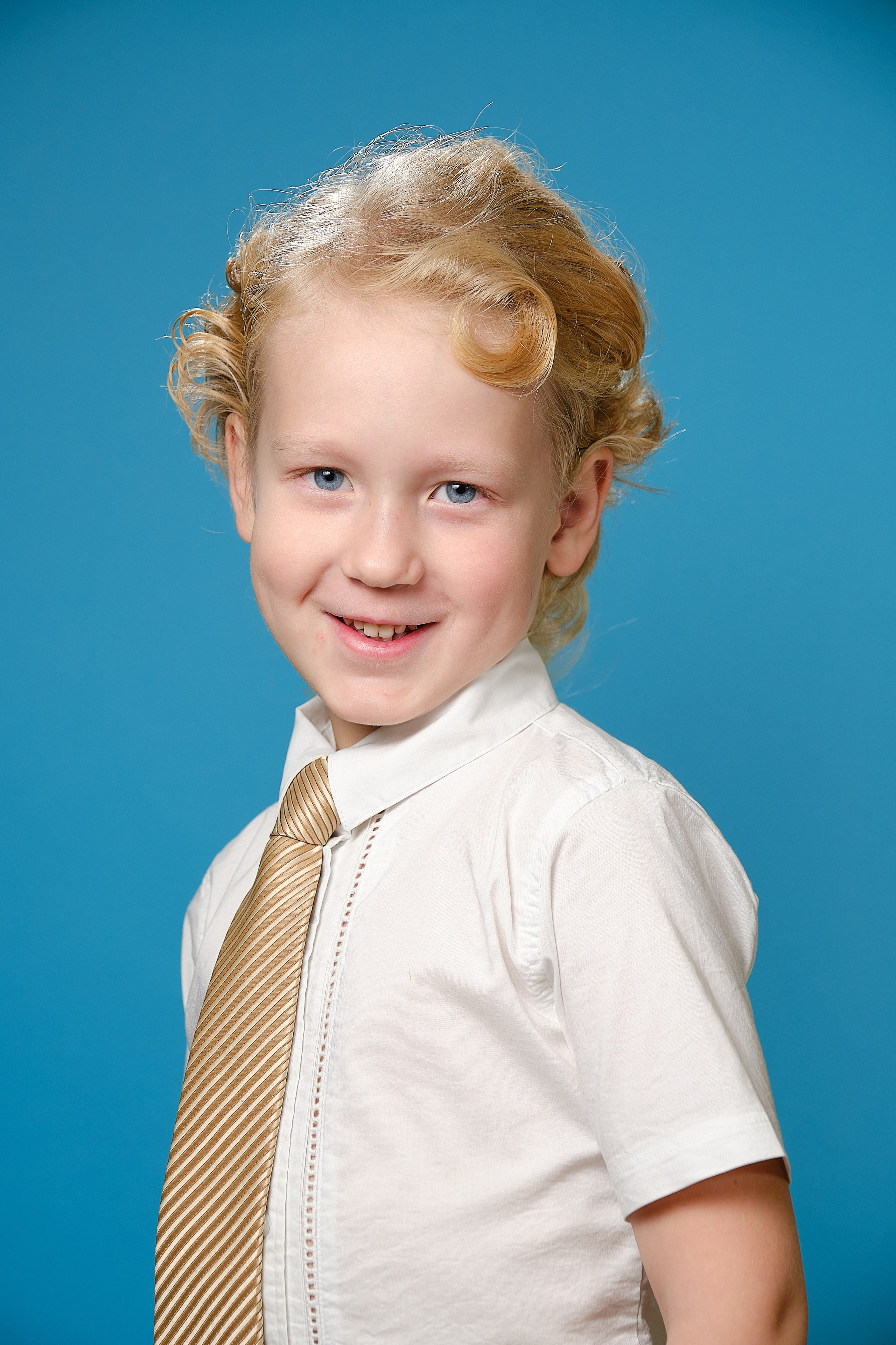 крупный портрет кудрявого светлого мальчика в галстуке