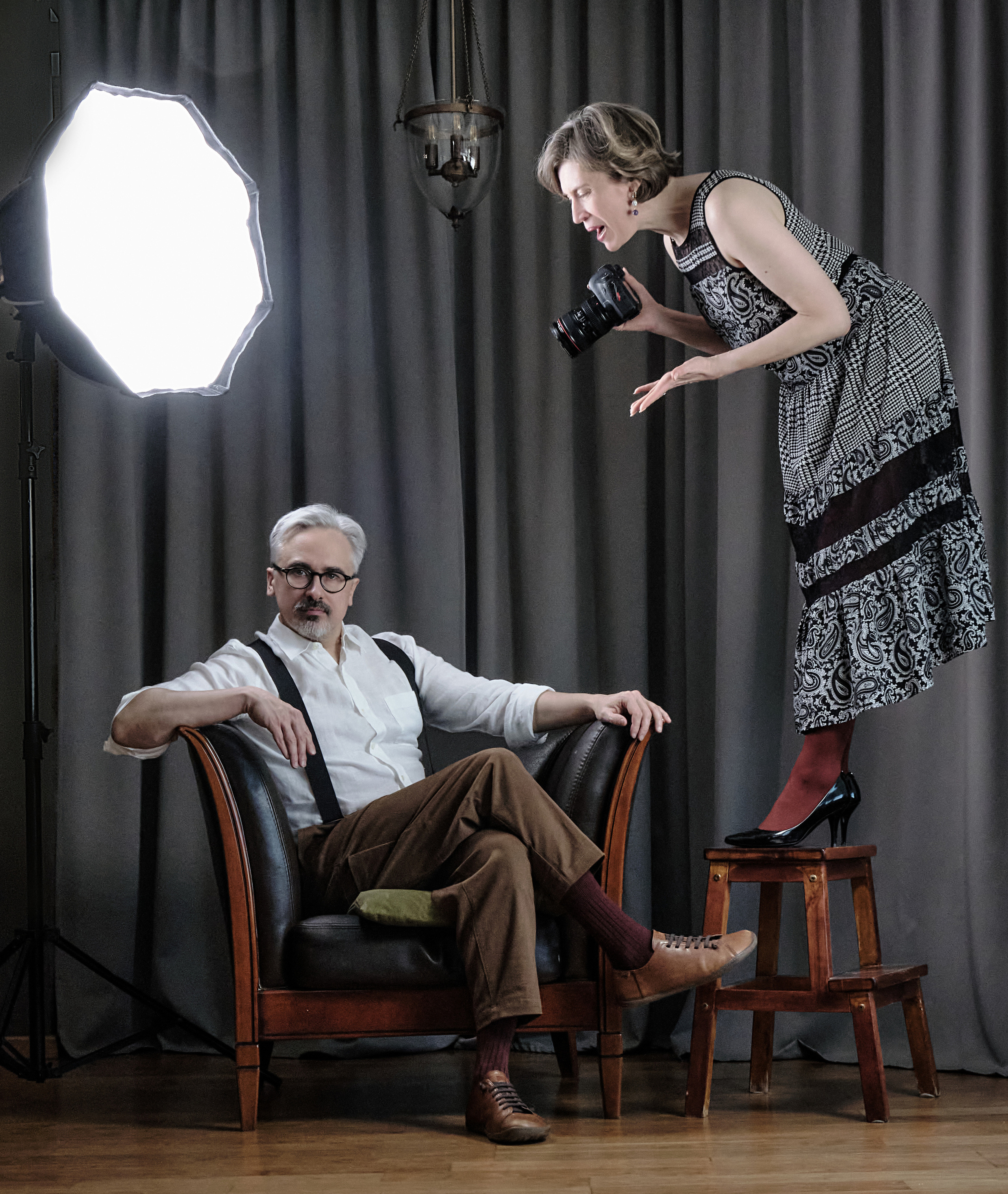 Женщина фотограф подсказывает мужчине какую позу принять на кресле, чтобы получить удачный ракурс на фото