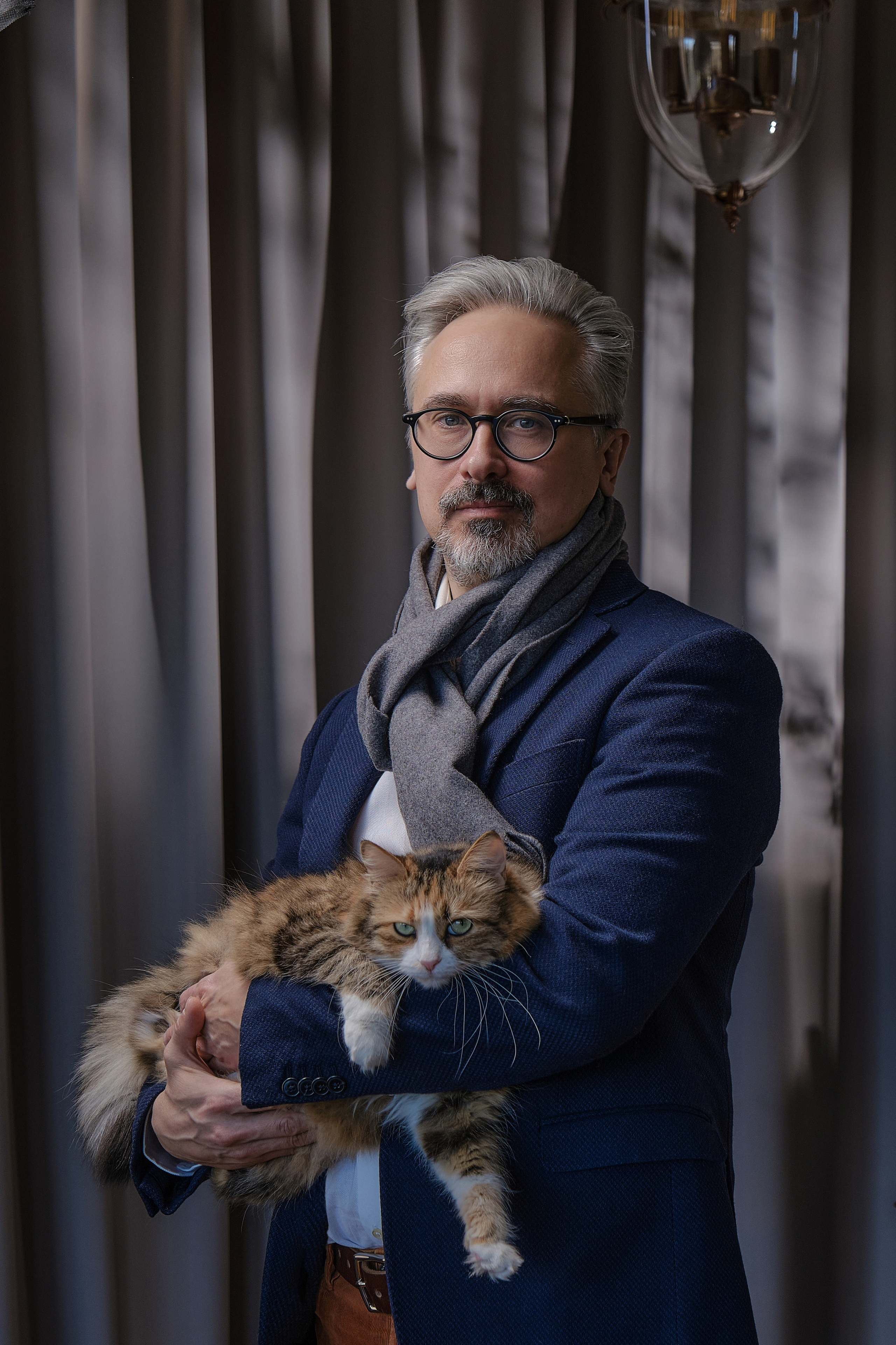 Портрет мужчины средних лет с седой бородой и усами в синем пиджаке с кошкой на руках 
