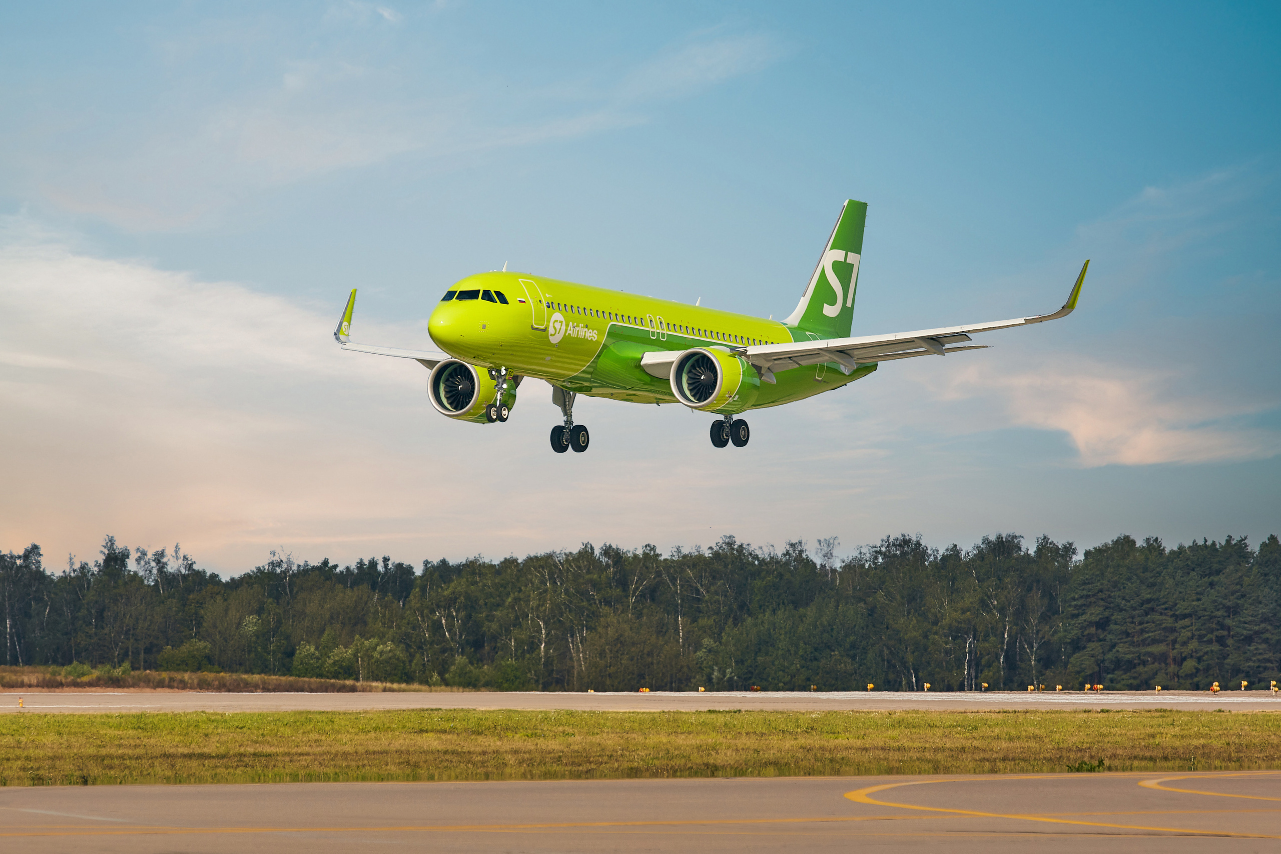 Самолет Airbus A320neo в зеленой ливрее авиакомпании S7 Airlines приземляется на посадочную полосу аэропорта 