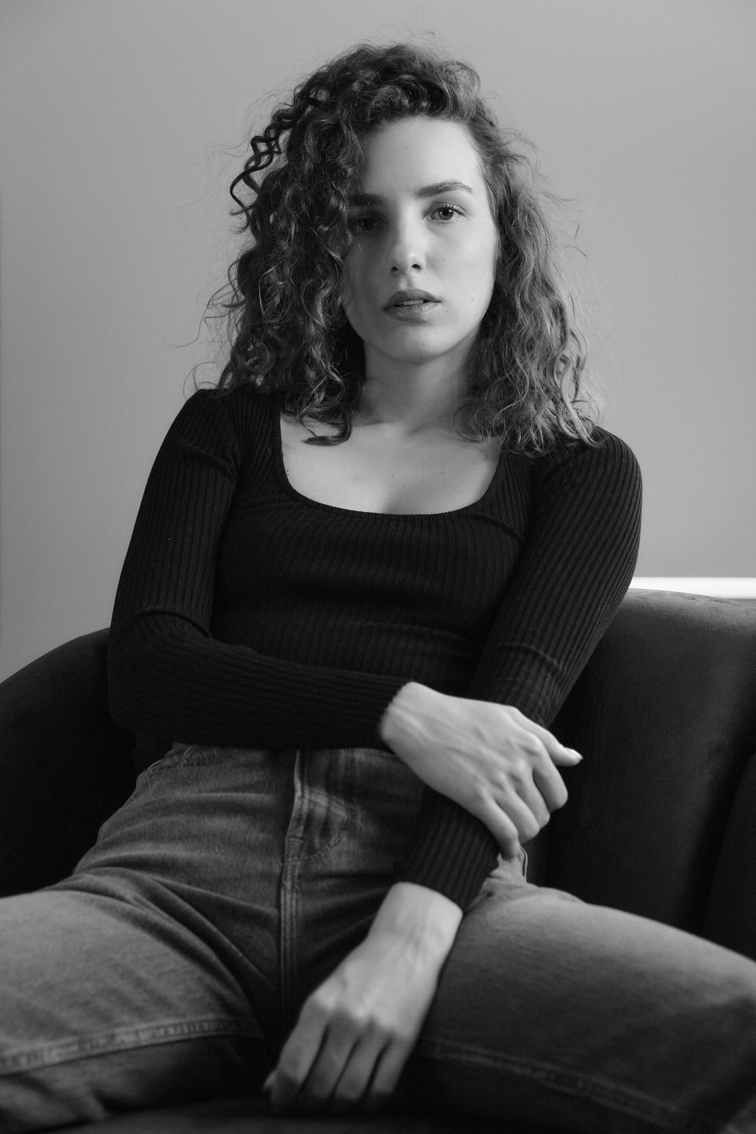 Молодая красивая модель позирует перед камерой, сидя на кресле 