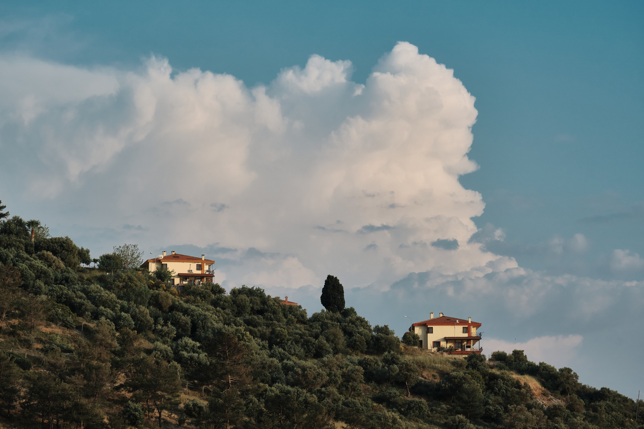 Склон прибрежного поселения с домиками на фоне красивых облаков