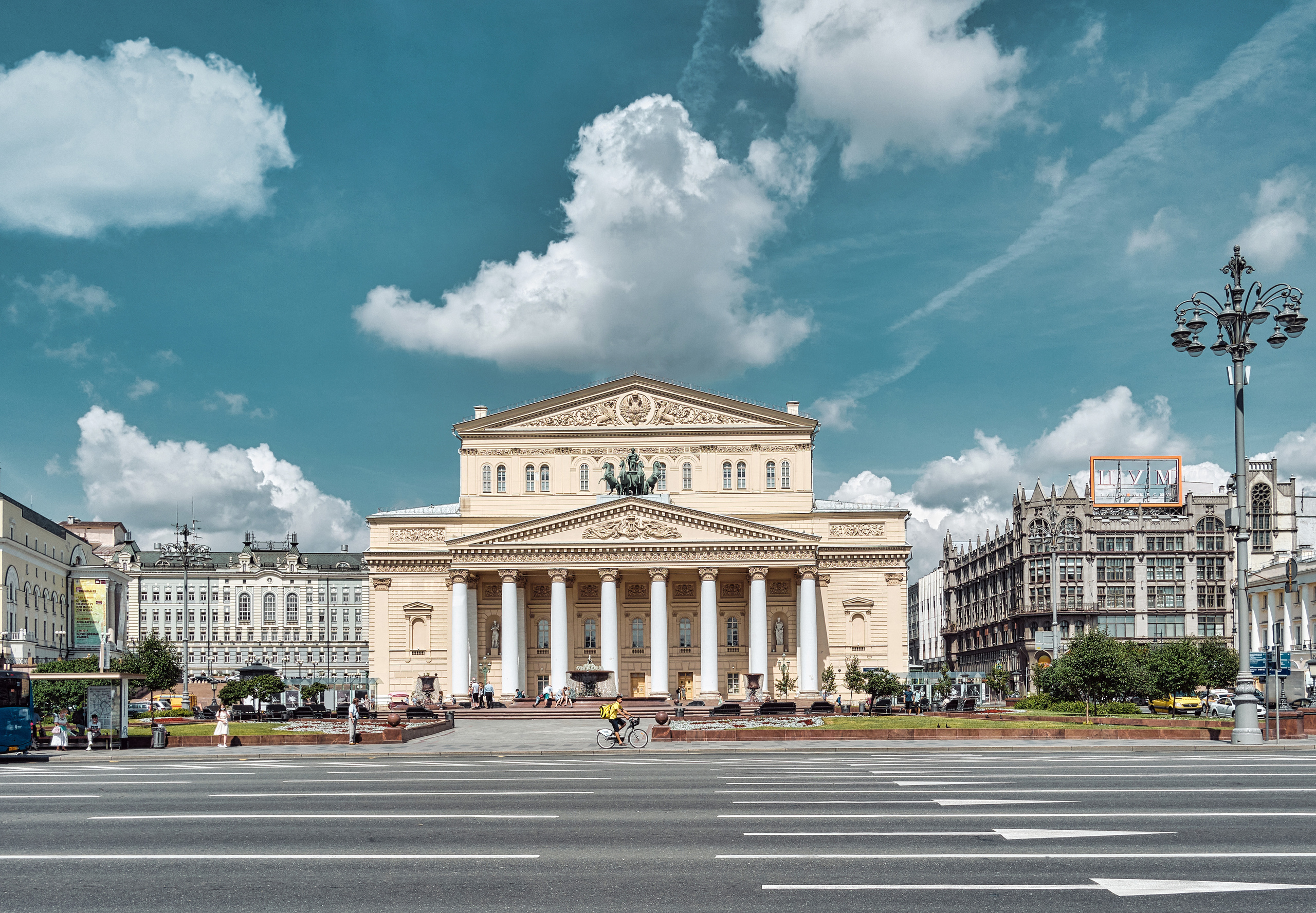 Московский Большой театр, освещенный летним солнцем на фоне облаков
