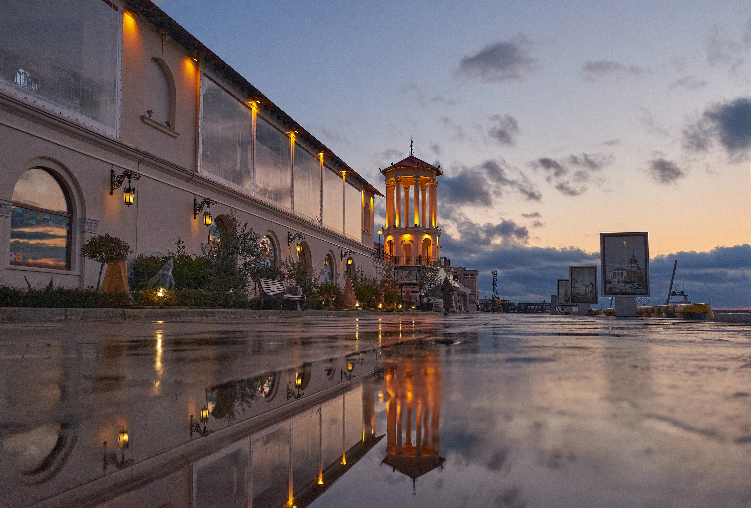 Боковая галерея здания морского вокзала в Сочи отражается в мокром асфальте на фоне вечерних облаков