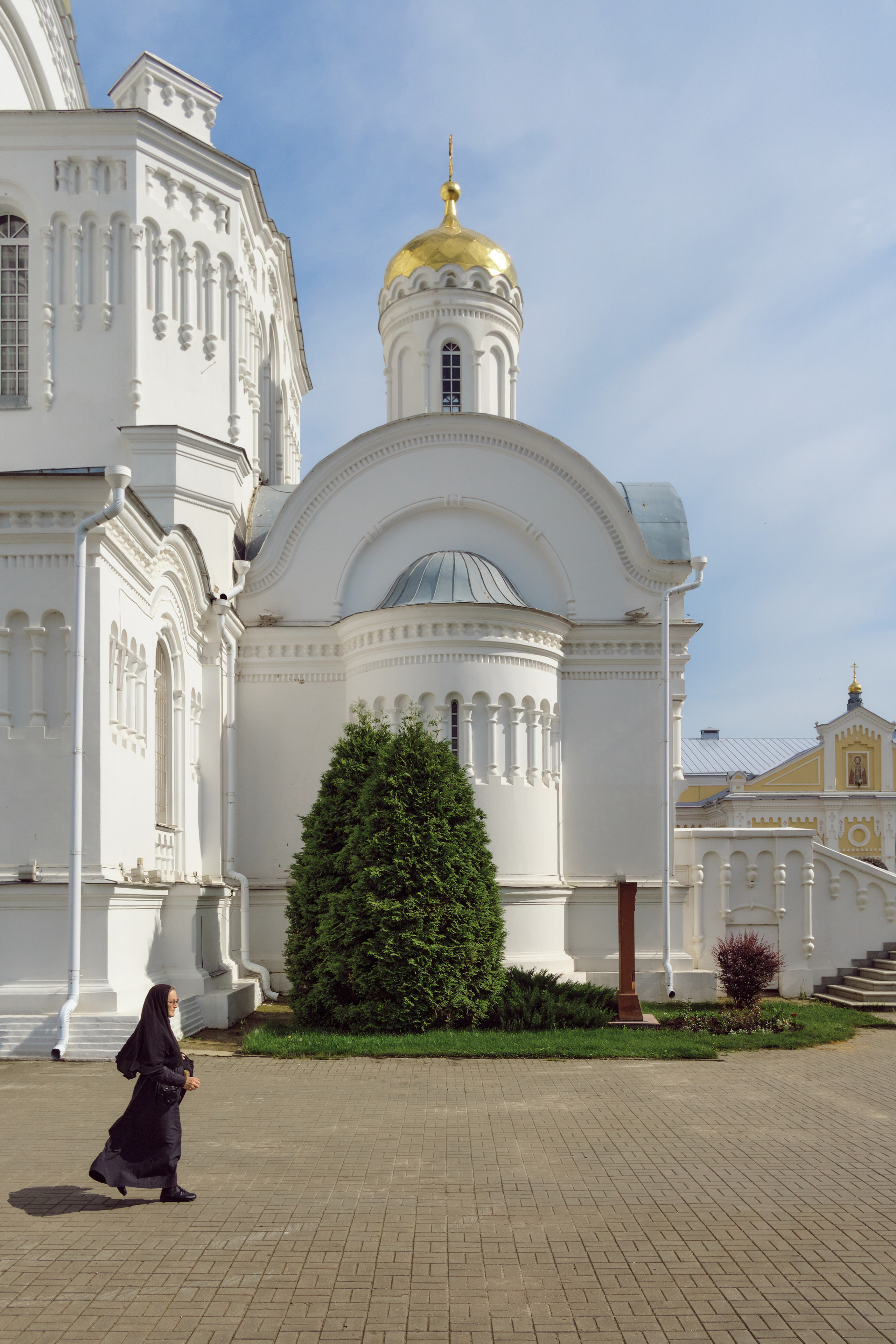 Монахиня идет по территории монастыря в Дивеево на фоне церкви