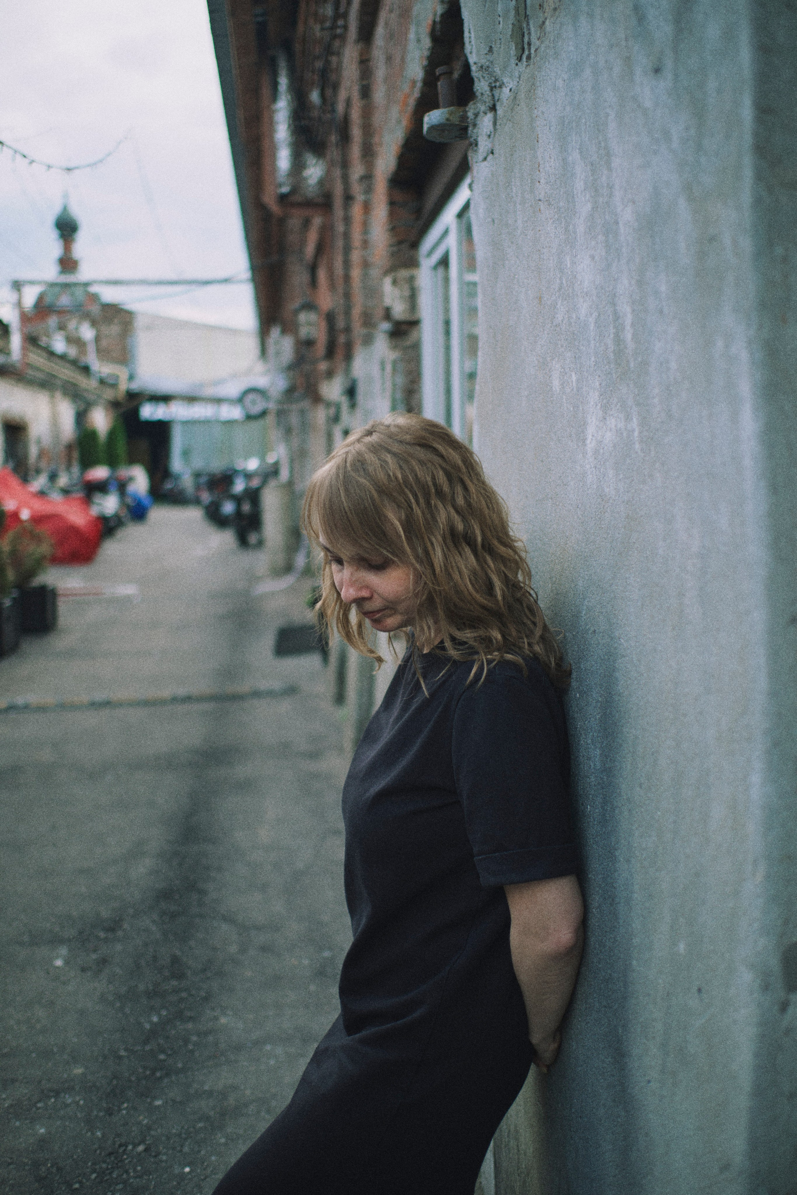 Женщина стоит у стены, задумавшись