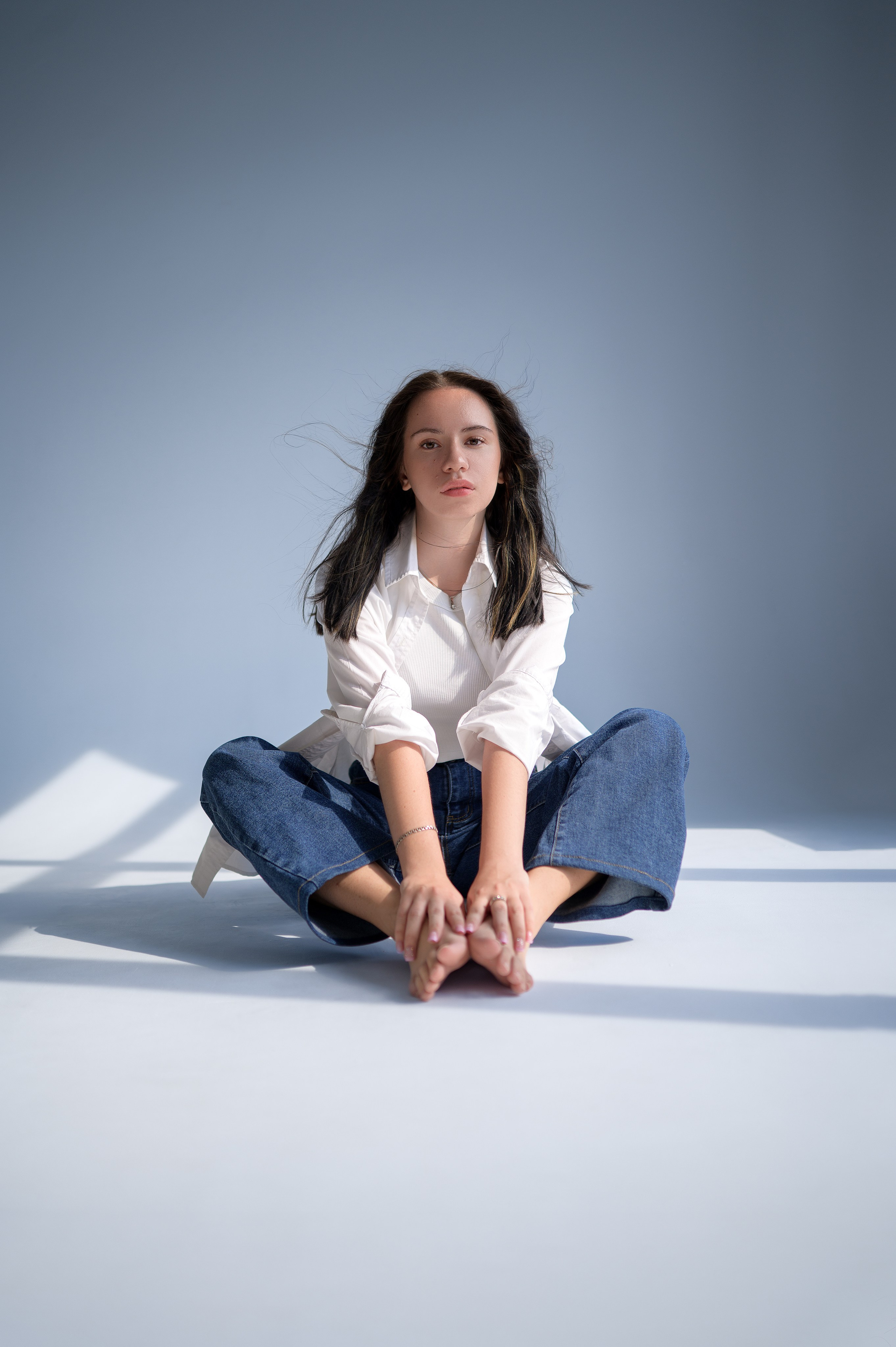 Фотосессия в студии «Рассвет» (Волгодонск): модель в рубашке и джинсах на циклораме. Естественный свет из окна формирует выразительные лучи